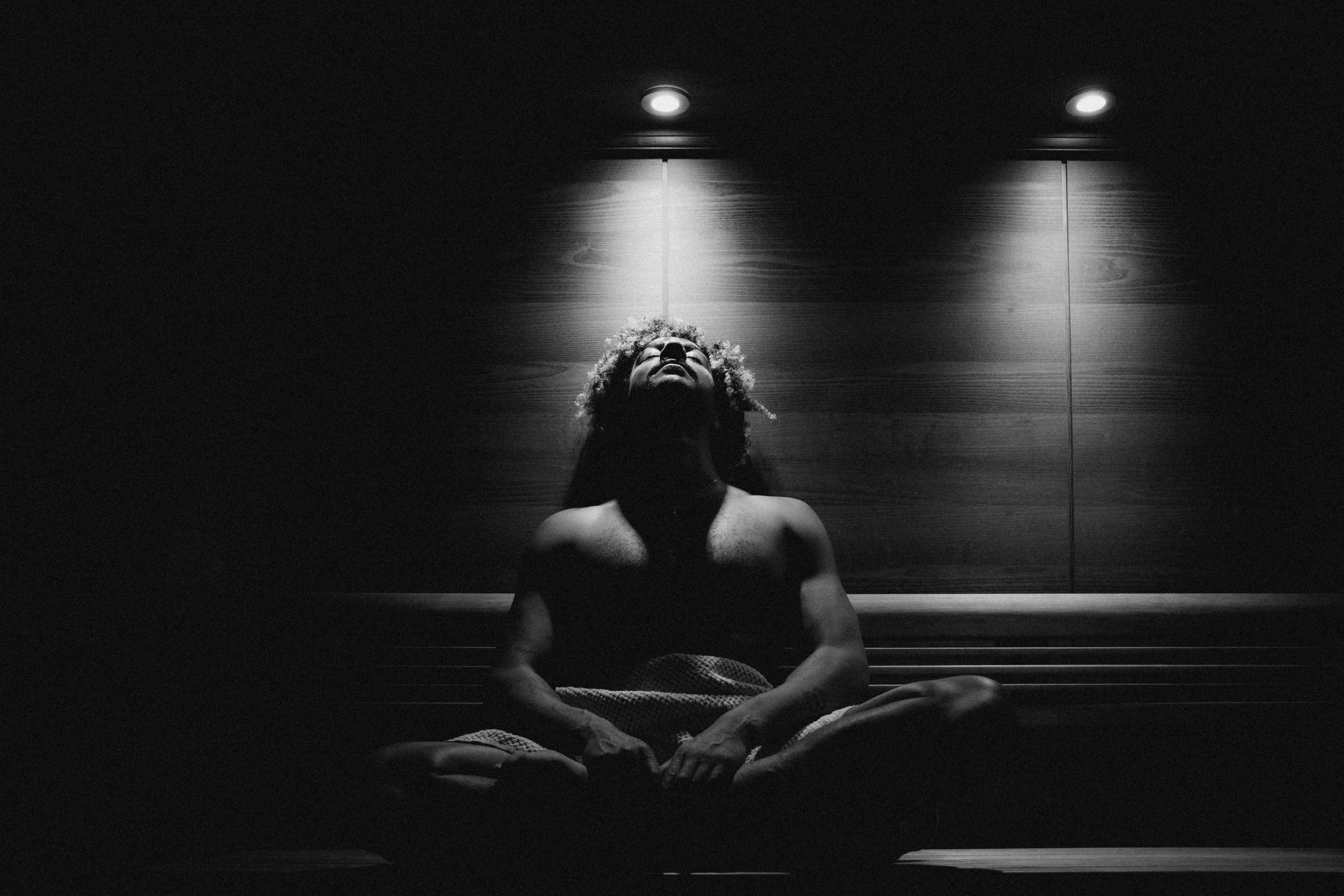 A dark setting with a figure illuminated by two overhead lights, creating a dramatic contrast.