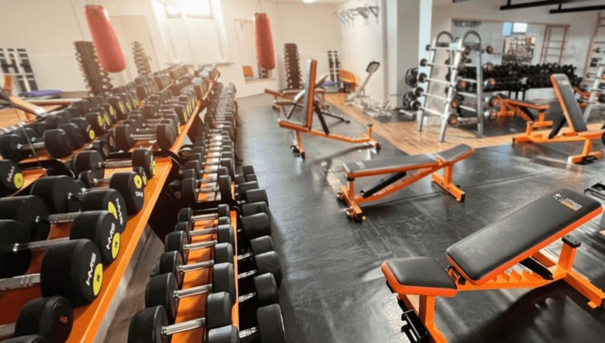 Panoramatický pohled na posilovnu — činky, lavice a boxovací pytle