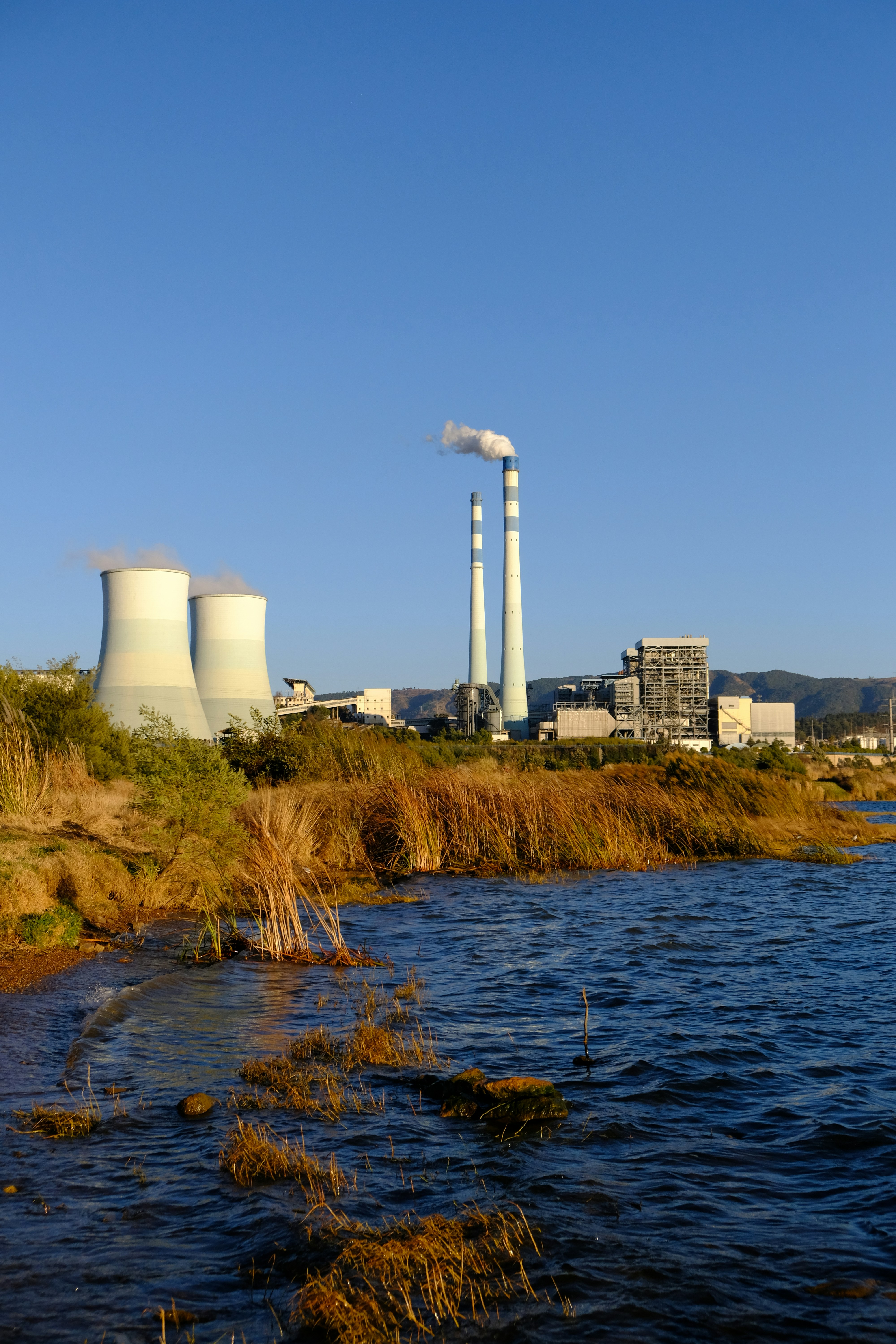 a body of water with a factory in the background
