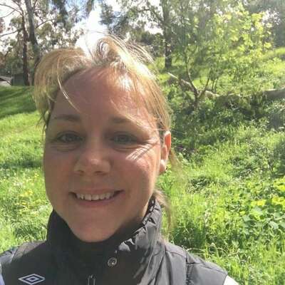 Femme de face en train de sourire dans une campagne.