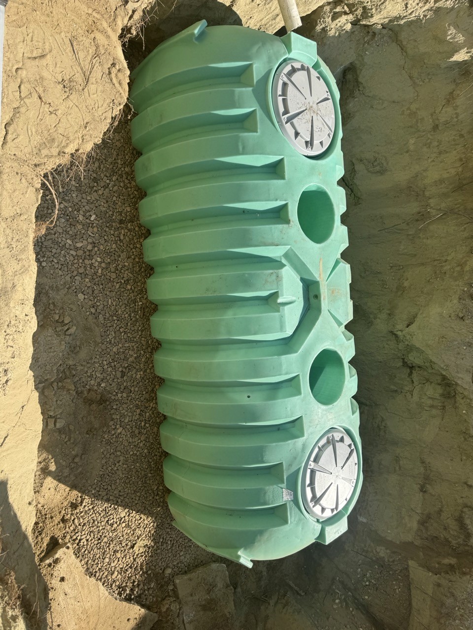 Green septic pump chamber set in a sand bed, by A&M Construction Enterprises