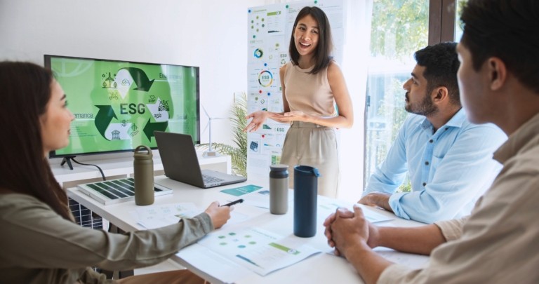 A diverse team collaborating in a meeting room with laptops, engaged in discussion around a table