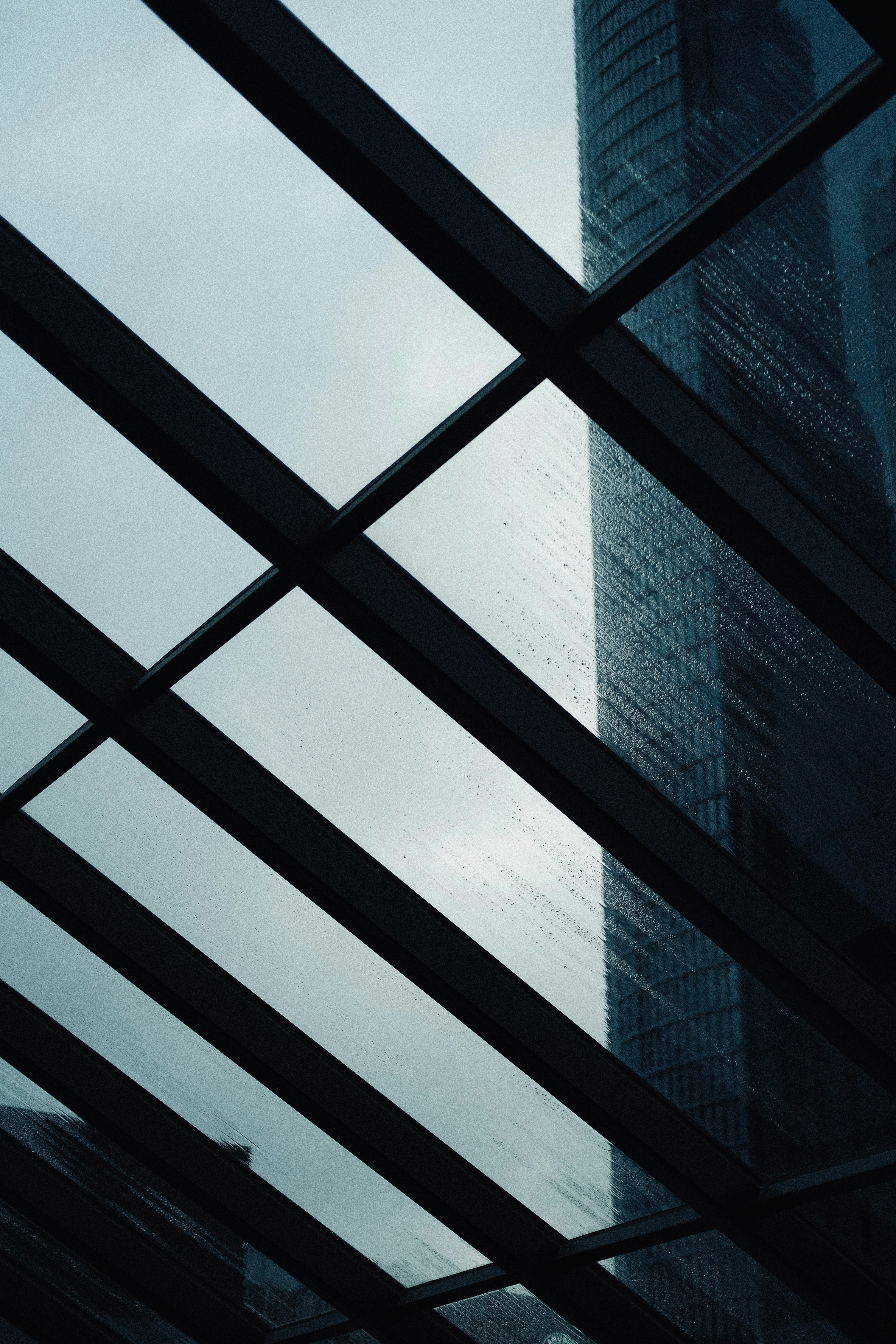 Modern skyscraper viewed through glass ceiling on a rainy day