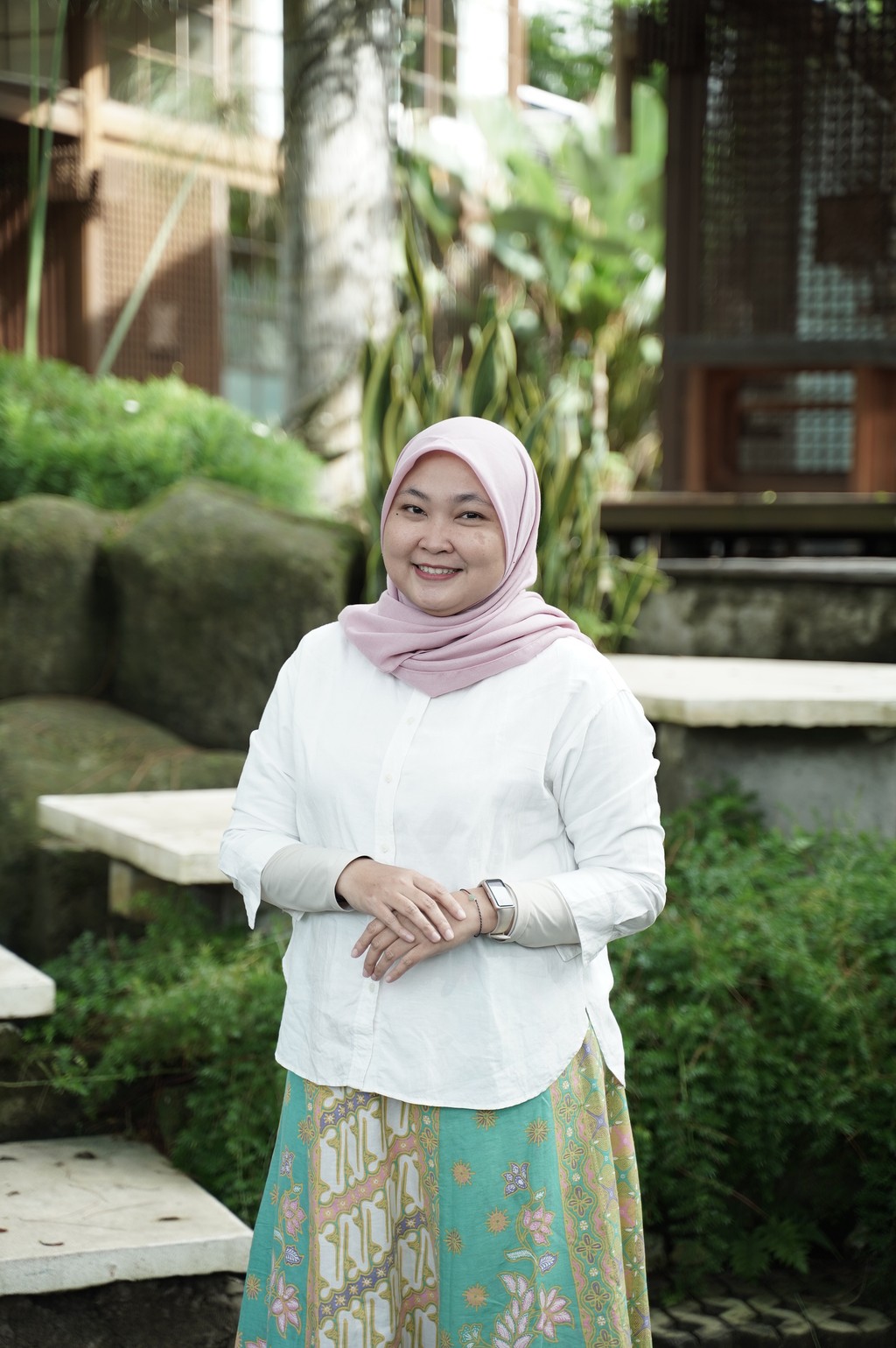 A winding road cuts through rocky terrain, surrounded by patches of green grass and illuminated by sunlight.