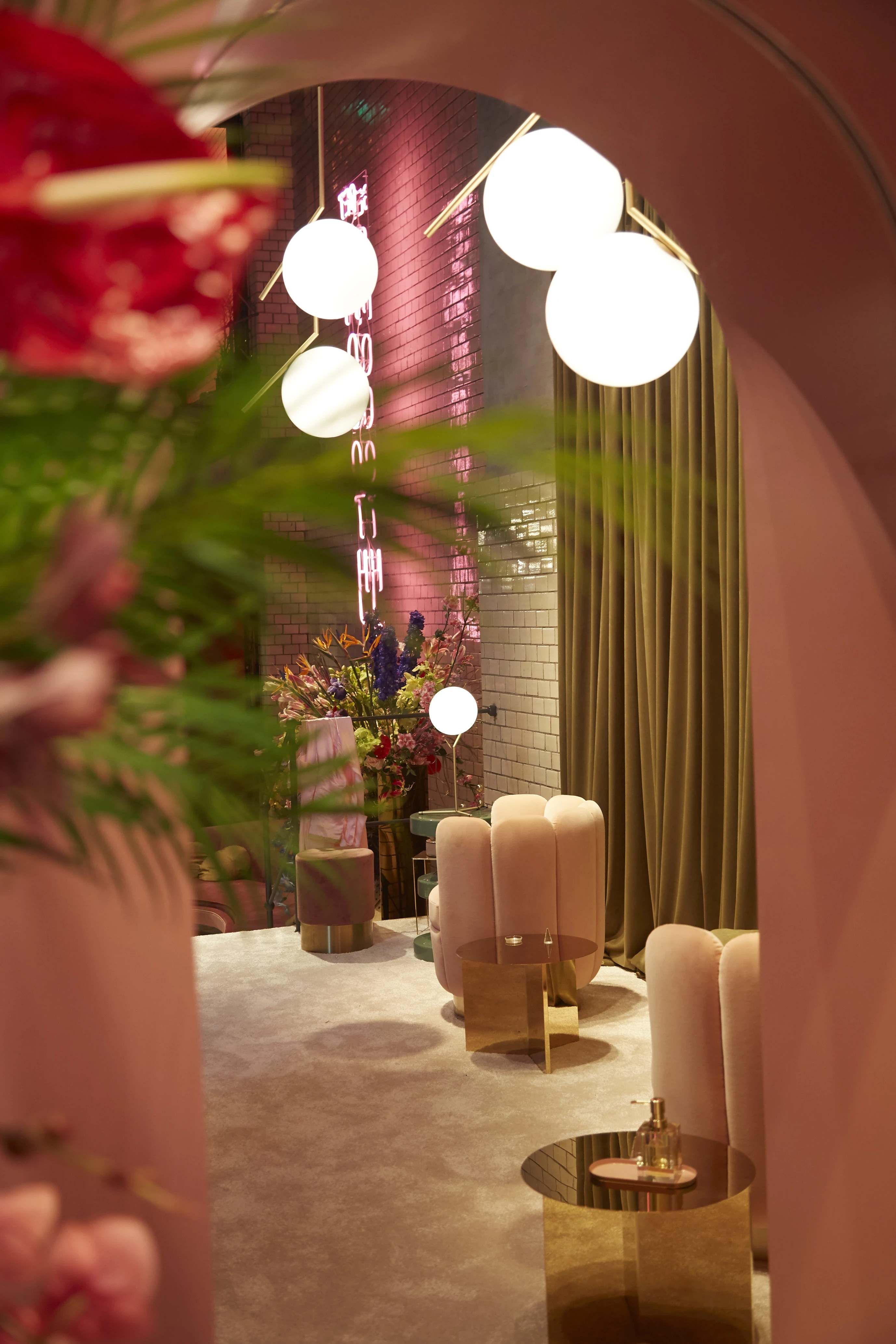 View through a pink arch onto velvet poufs and glowing globe lamps in the Klarna pop-up at Berlin Fashion Week.