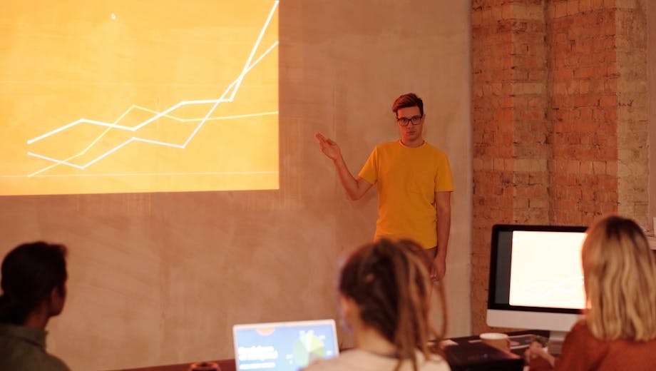 A young man gives a presentation on data analysis in a modern office setting.