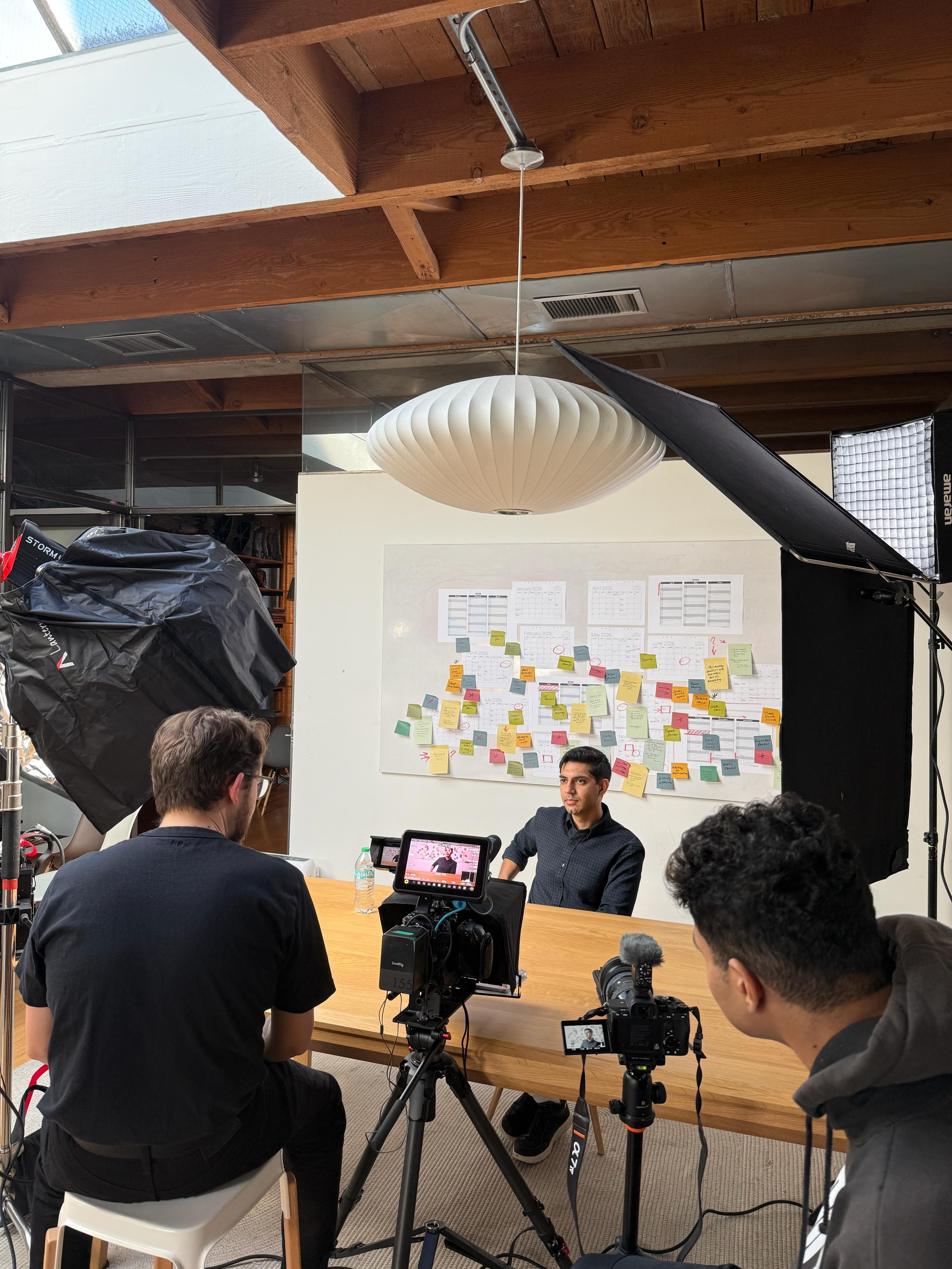 A talent recruiter with a soft smile working on her laptop in the office. The angle is on her face so we can't see what's is on the screen. She is wearing a blazer 