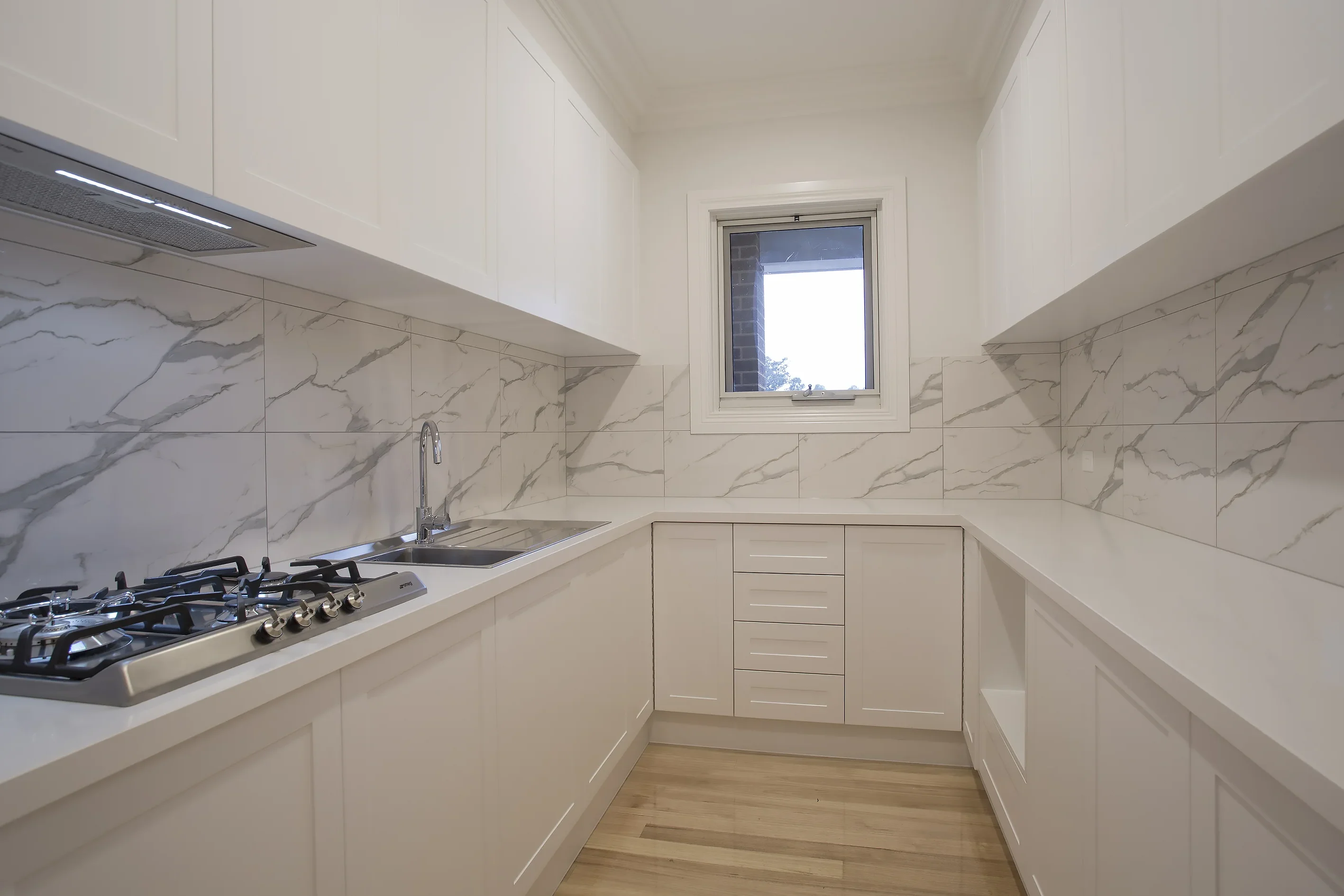 Butler's pantry with marble-look tiled splashback, stainless gas cooktop, undermount sink and white cabinetry
