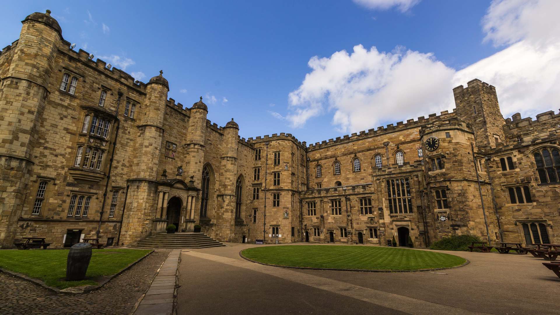 Interior courtyard of Durham Castle, a historic sandstone building with battlements, under a blue sky
