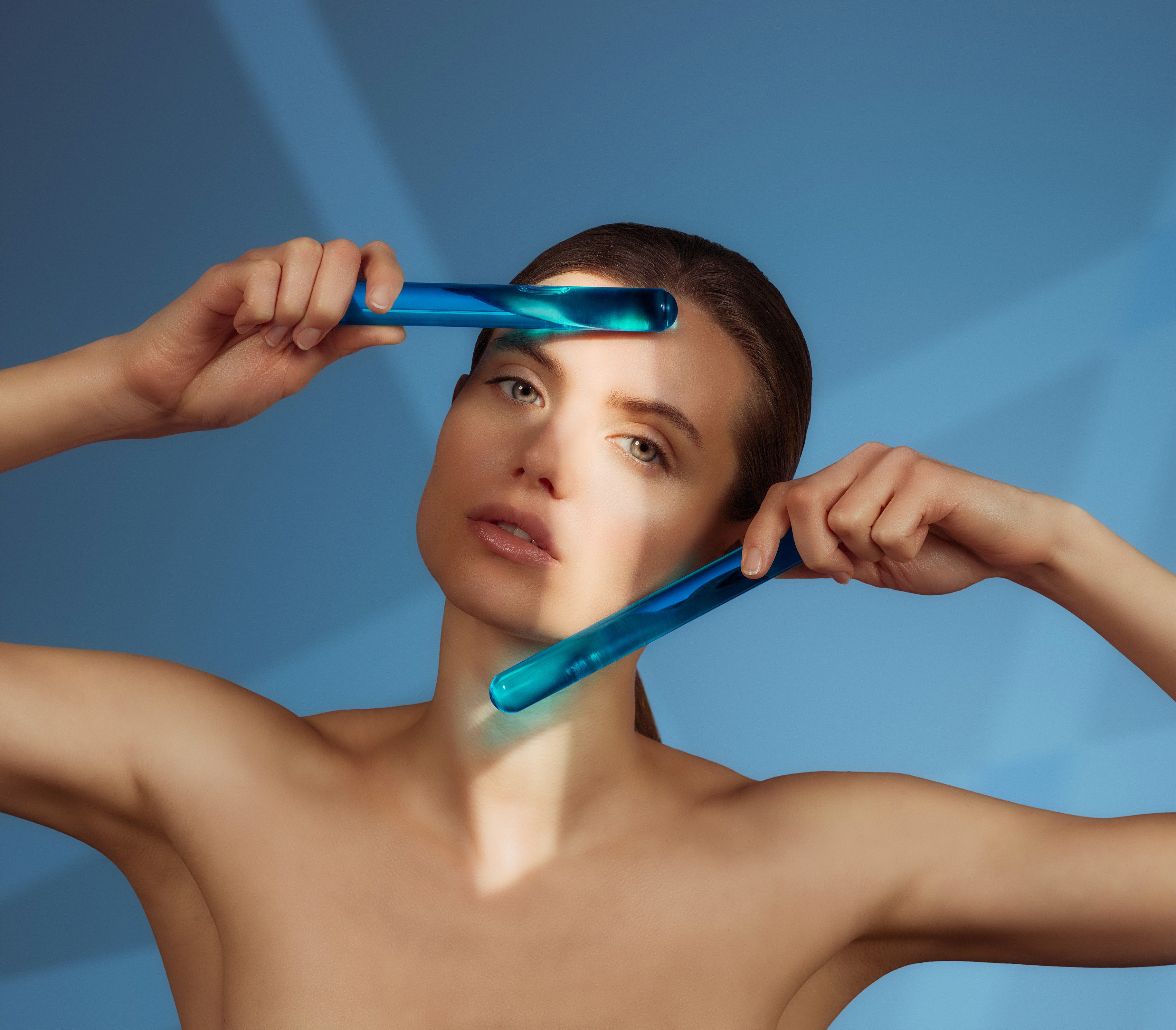 Model posing with blue glass rods in photography for Saypha hyaluronic acid dermal fillers