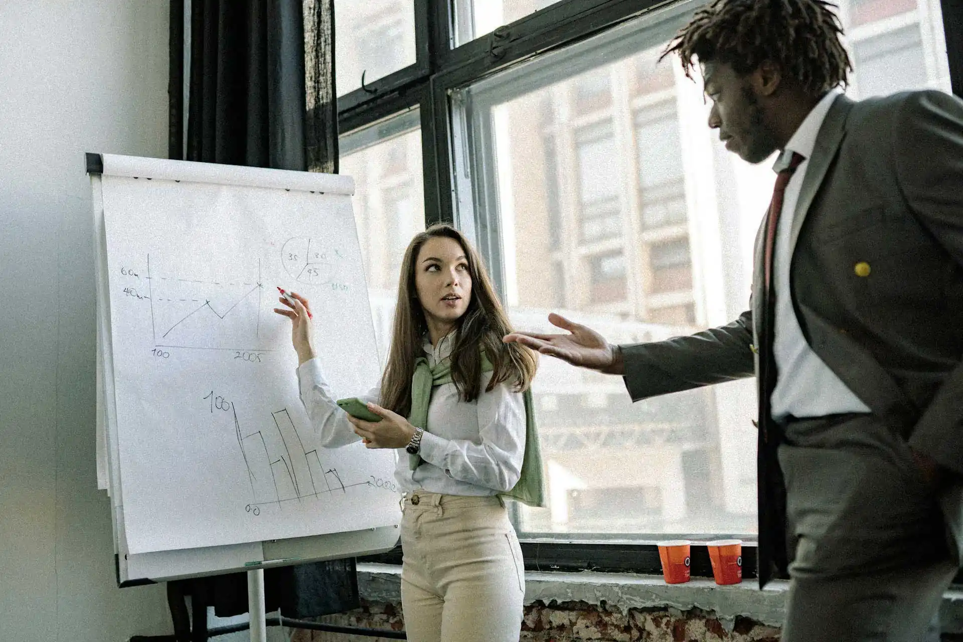 Woman pointing at whiteboard, man gesturing