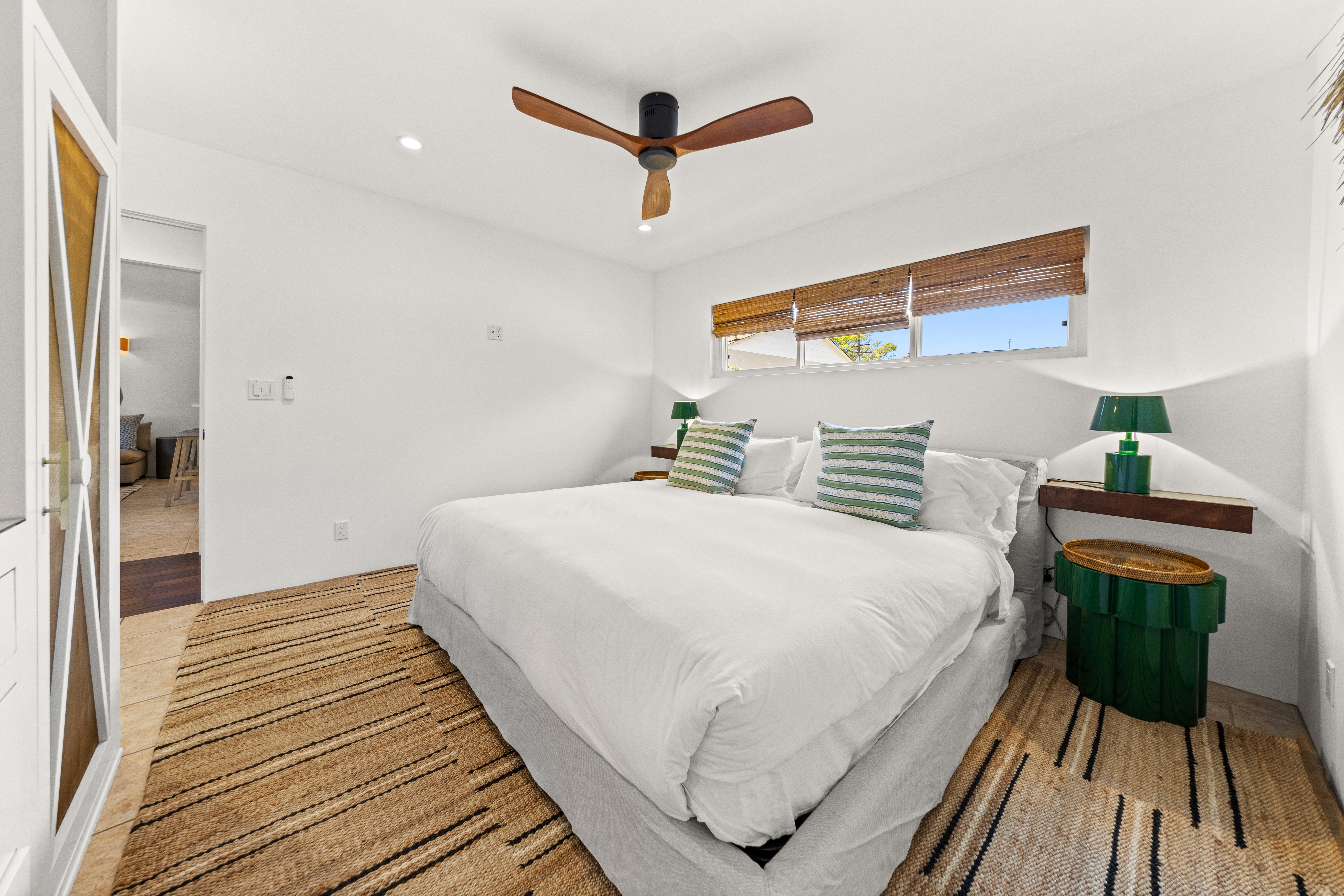 A sunny bedroom with fresh coastal textiles and sliding doors that open to views of the courtyard.