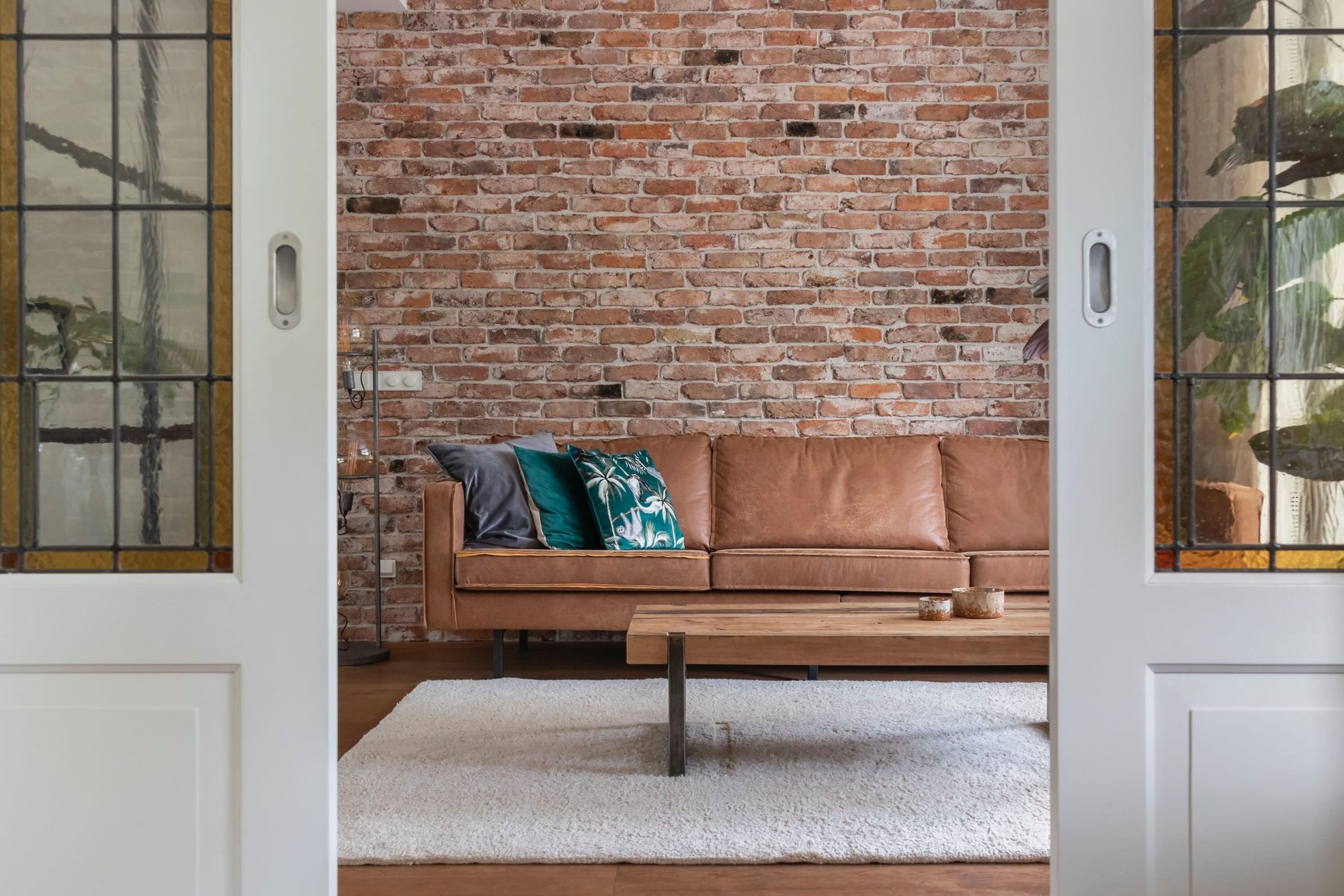 zithoek industriele stijl met brick wall en cognac leren bank met industriele tafel van oud hout
