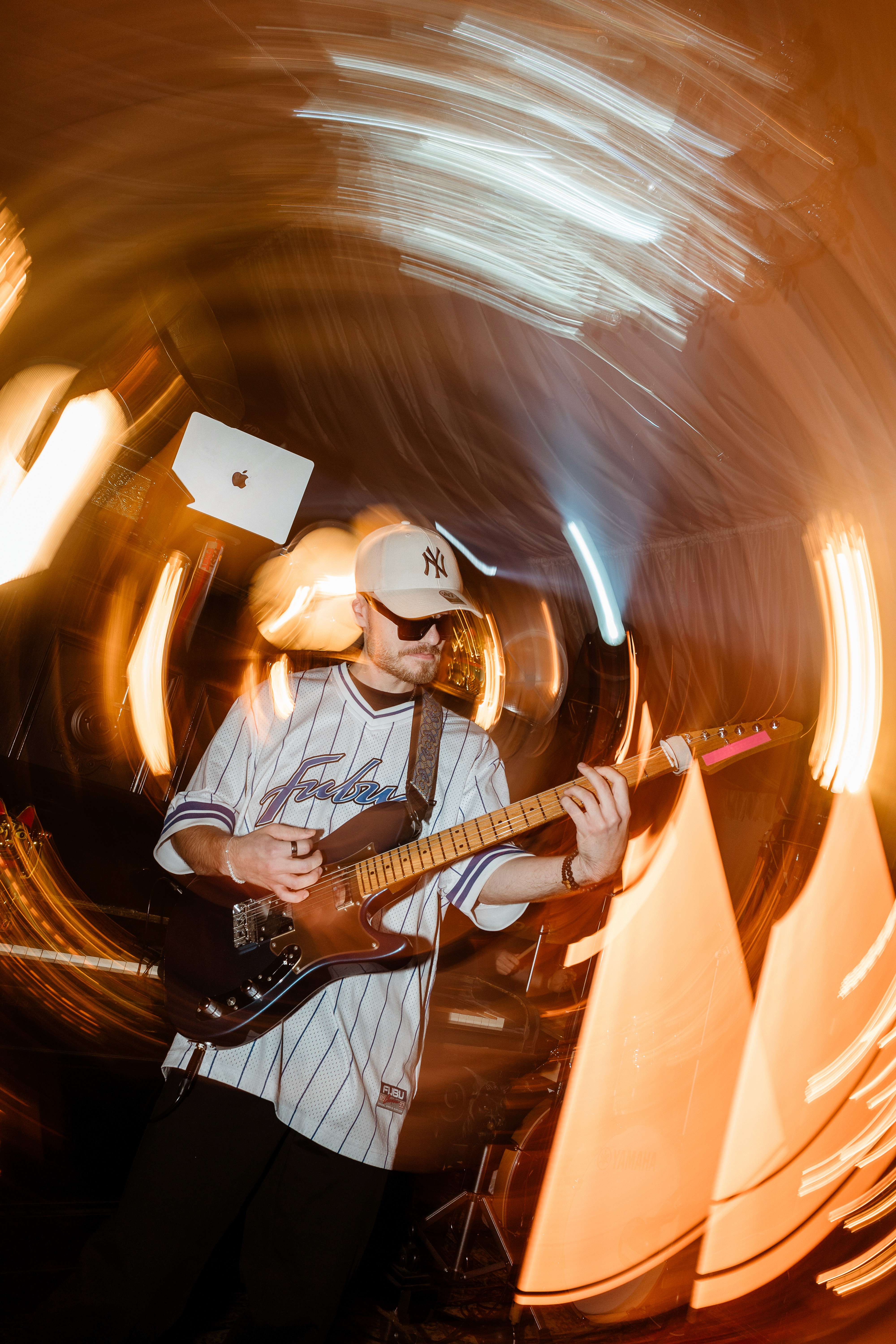 A person with shoulder-length blonde hair wearing a black newsboy cap and a black sweater.
