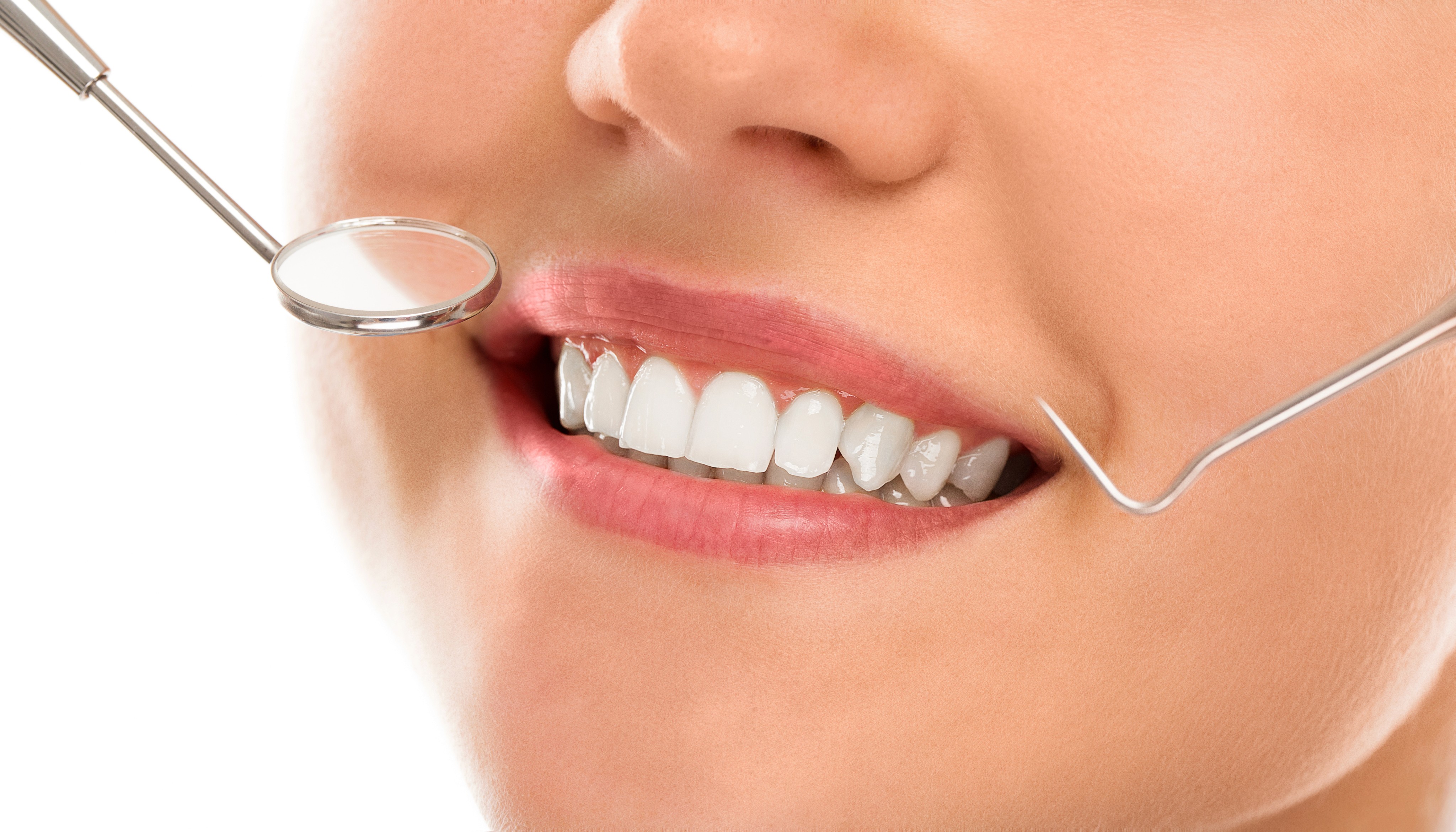 A close-up of a person's mouth with healthy teeth being examined with a dental mirror.