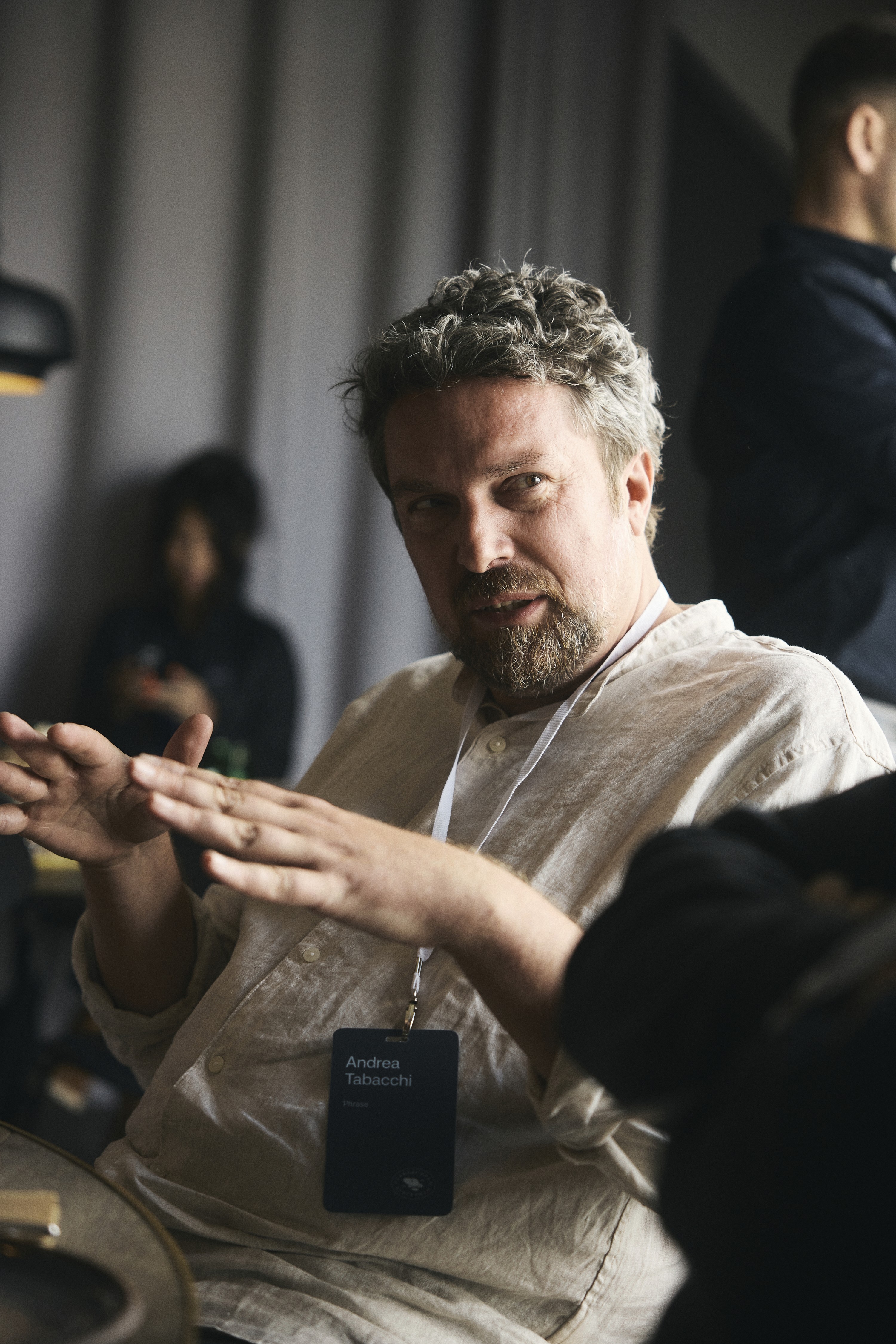 A surfer in a black wetsuit waxes a white surfboard on a misty beach, preparing for the water.