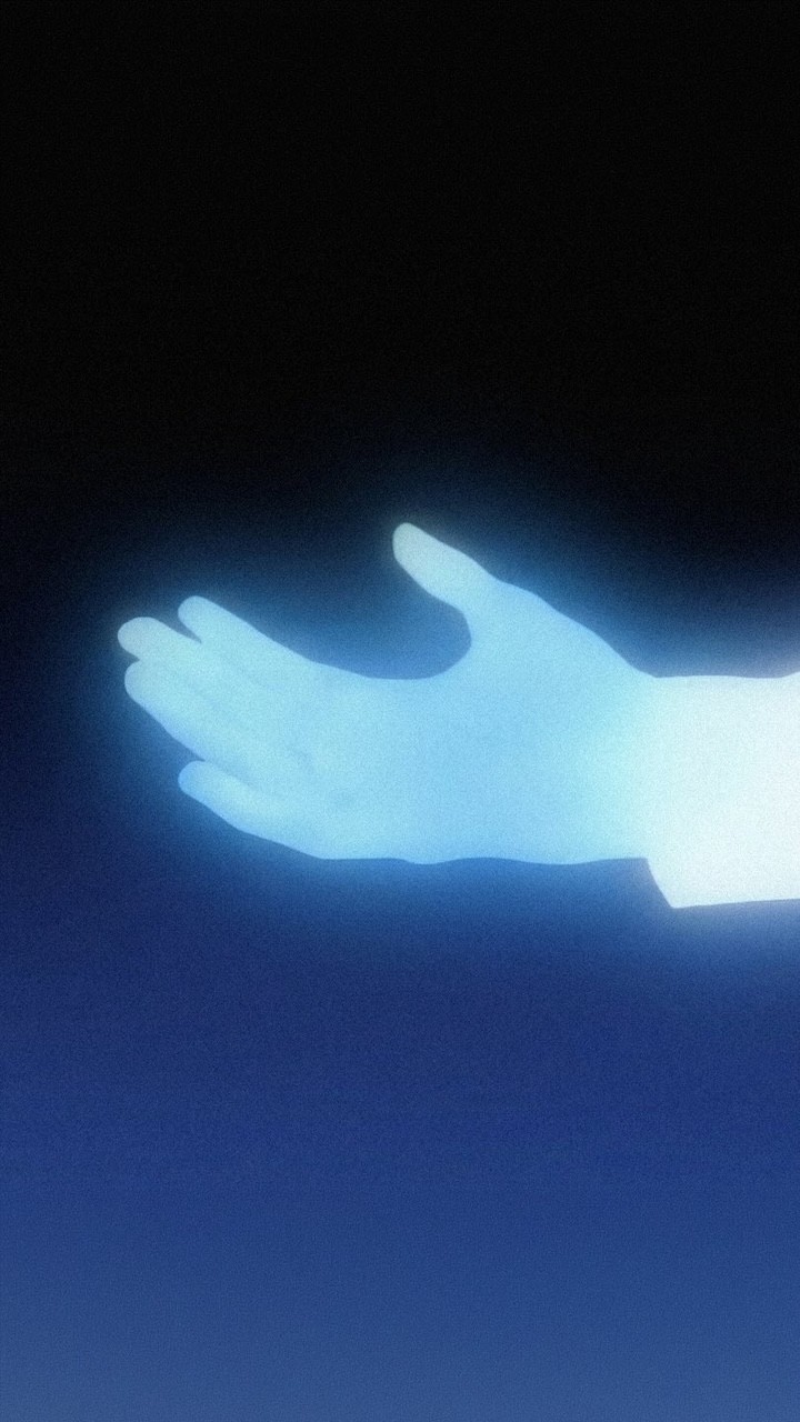 Glowing blue human hand emerging from darkness, softly illuminated with a grainy texture