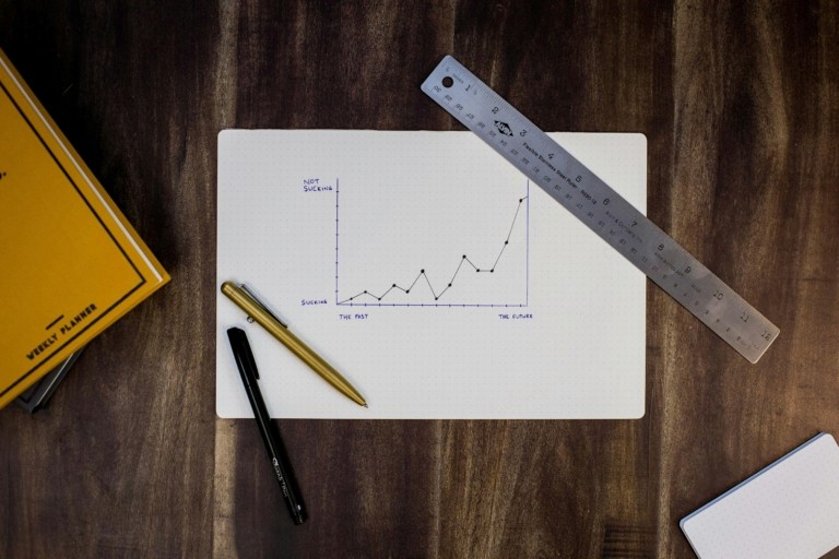 A hand-drawn growth chart on paper with a ruler and pen on a wooden desk, representing key performance metrics and business growth for care home group CEOs