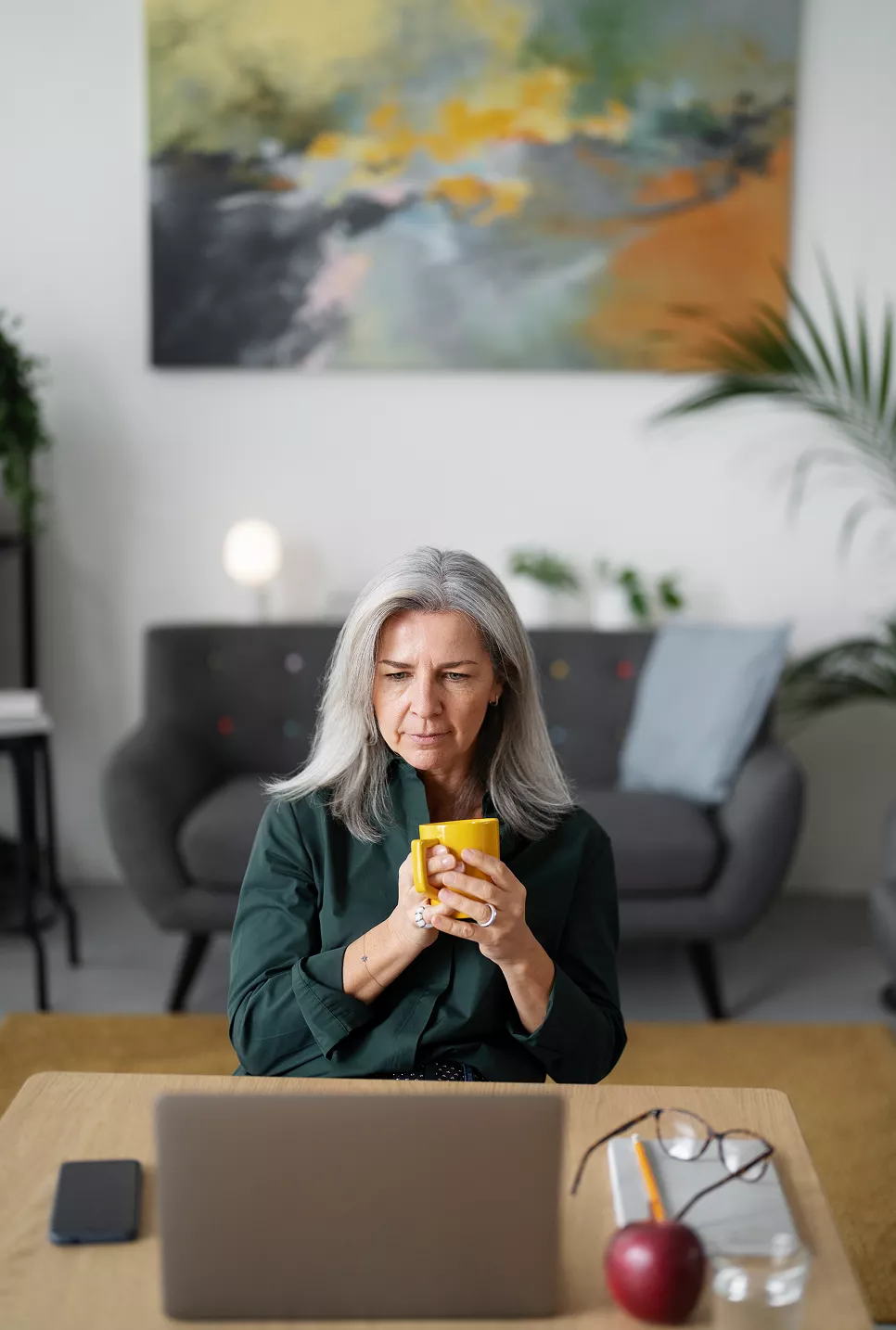 woman holding a mug and looking at laptop
