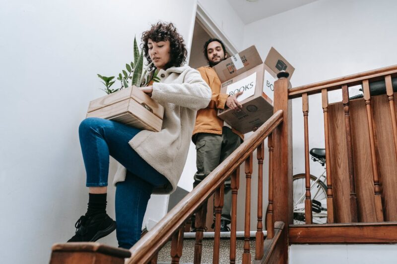 two movers carry boxes downstairs - the best day to move home might not be the most popular choice