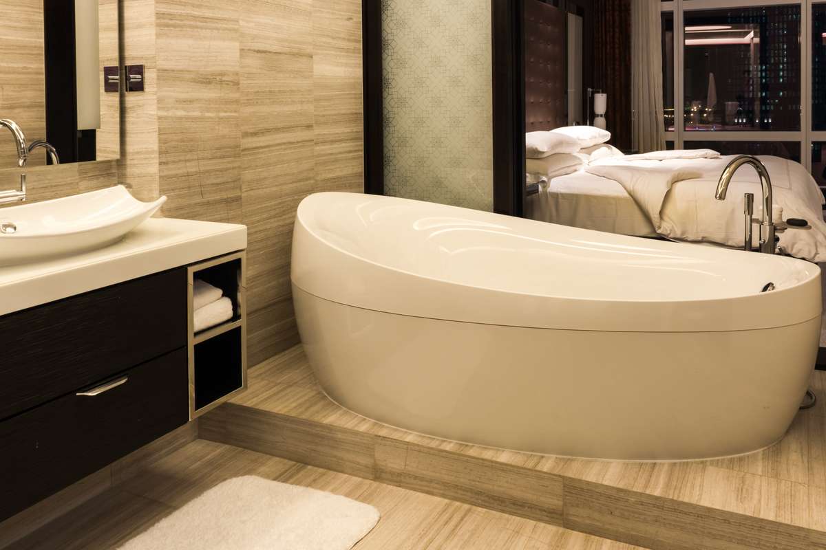 A modern bathroom features a large white oval soaking tub next to a dark wood vanity with a white vessel sink.