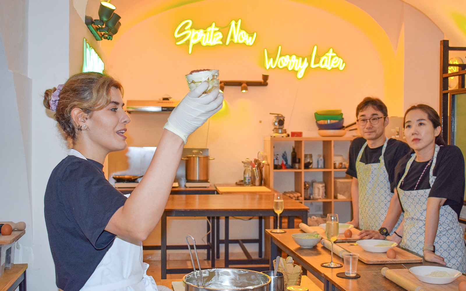 एक कुकिंग क्लास में प्रशिक्षक प्रतिभागियों के साथ टिरामिसू बनाने का तरीका दिखा रहे हैं।