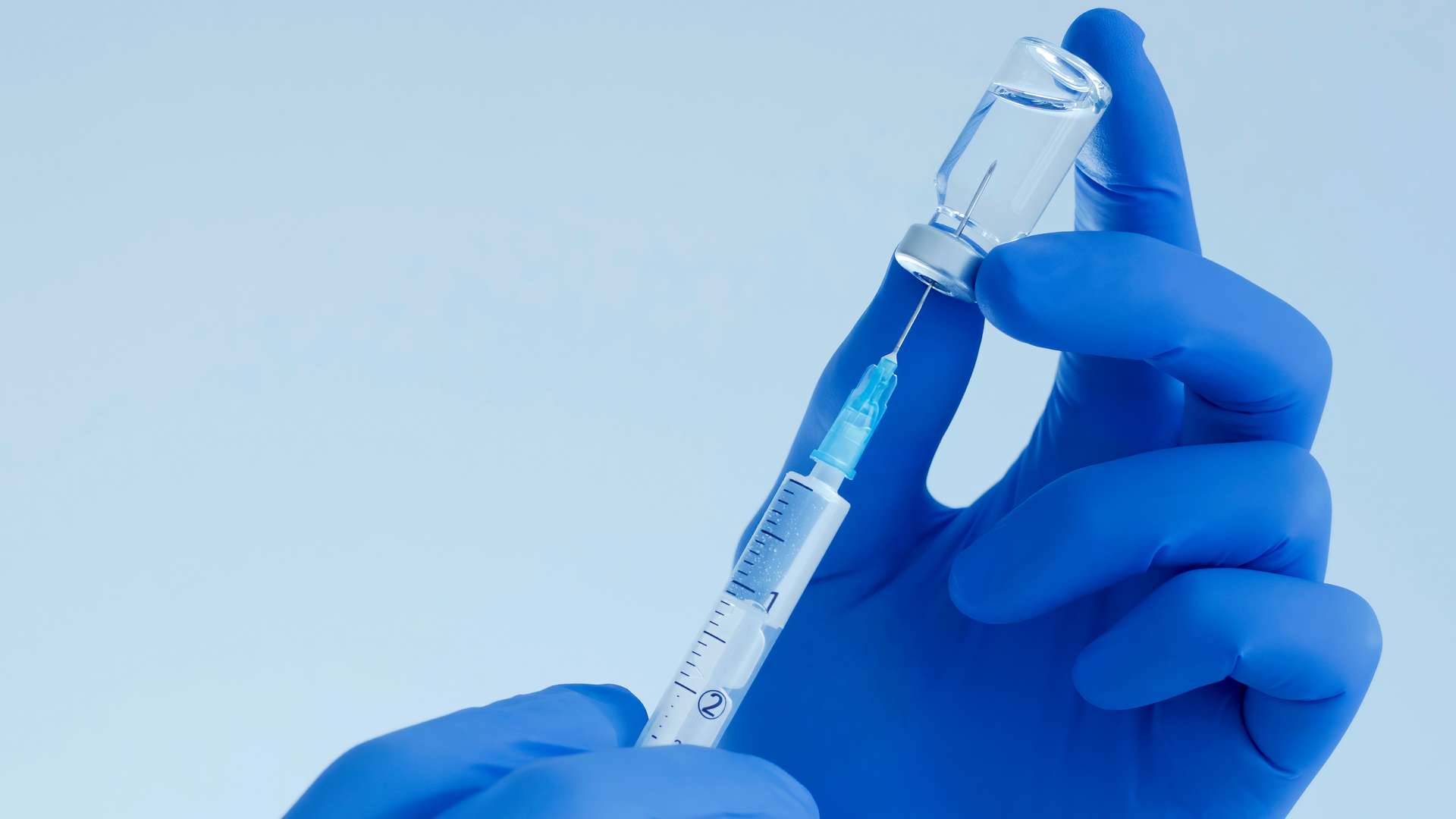 Doctor hands holding a vaccine bottle and syringe.