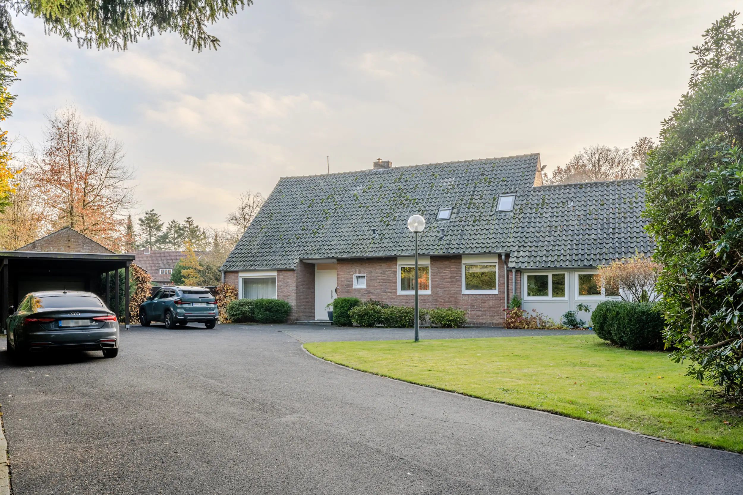Außenansicht eines Einfamilienhauses mit Einliegerwohnung in Bad Bentheim, Zufahrt mit Carport und gepflegter Vorgarten.