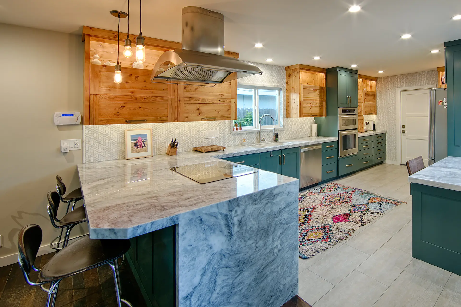 Open-plan kitchen with teal cabinets, wooden shelves, and stone breakfast bar in Huntington Beach Kitchen & Bath Remodel.
