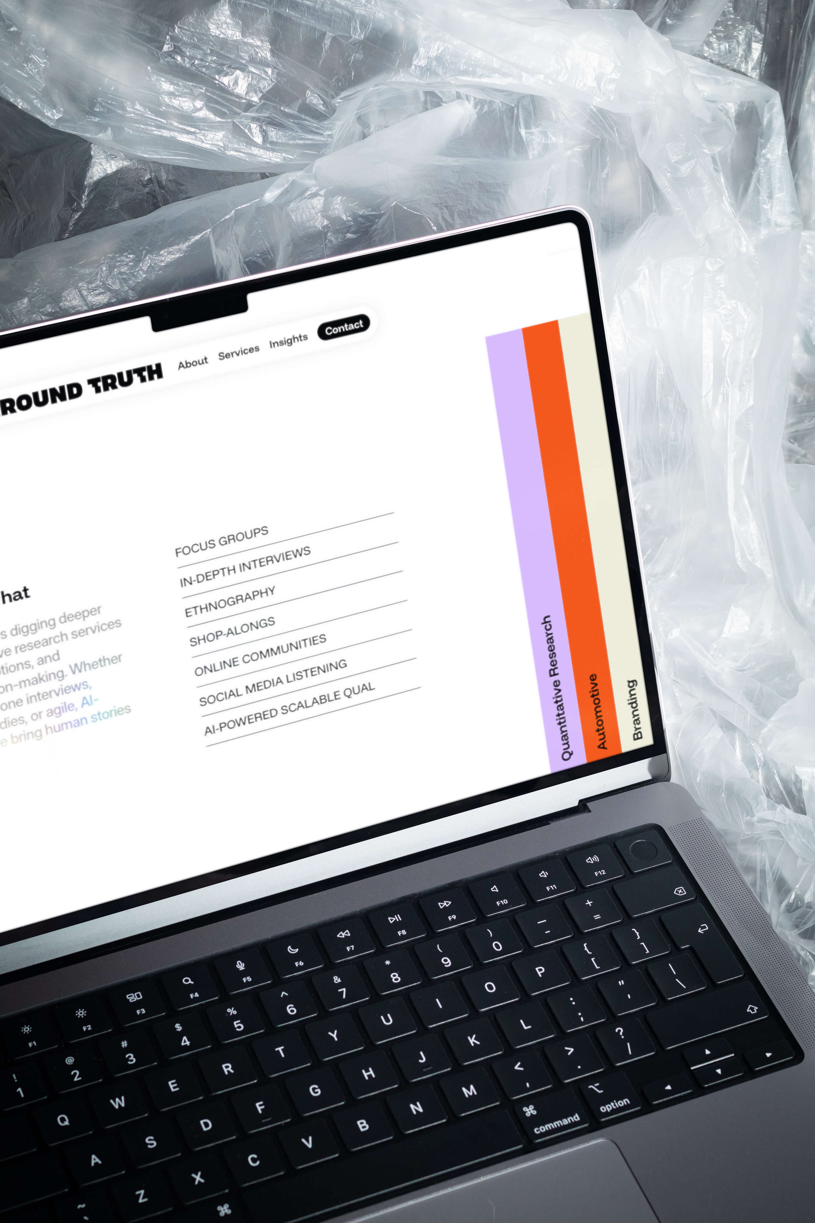 A laptop on a smoky surface displaying a website with colorful text and a white background.