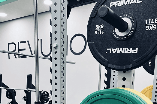 Čierne jednoručky, uterák a fľaša s vodou položené na stole vo fitnes centre.