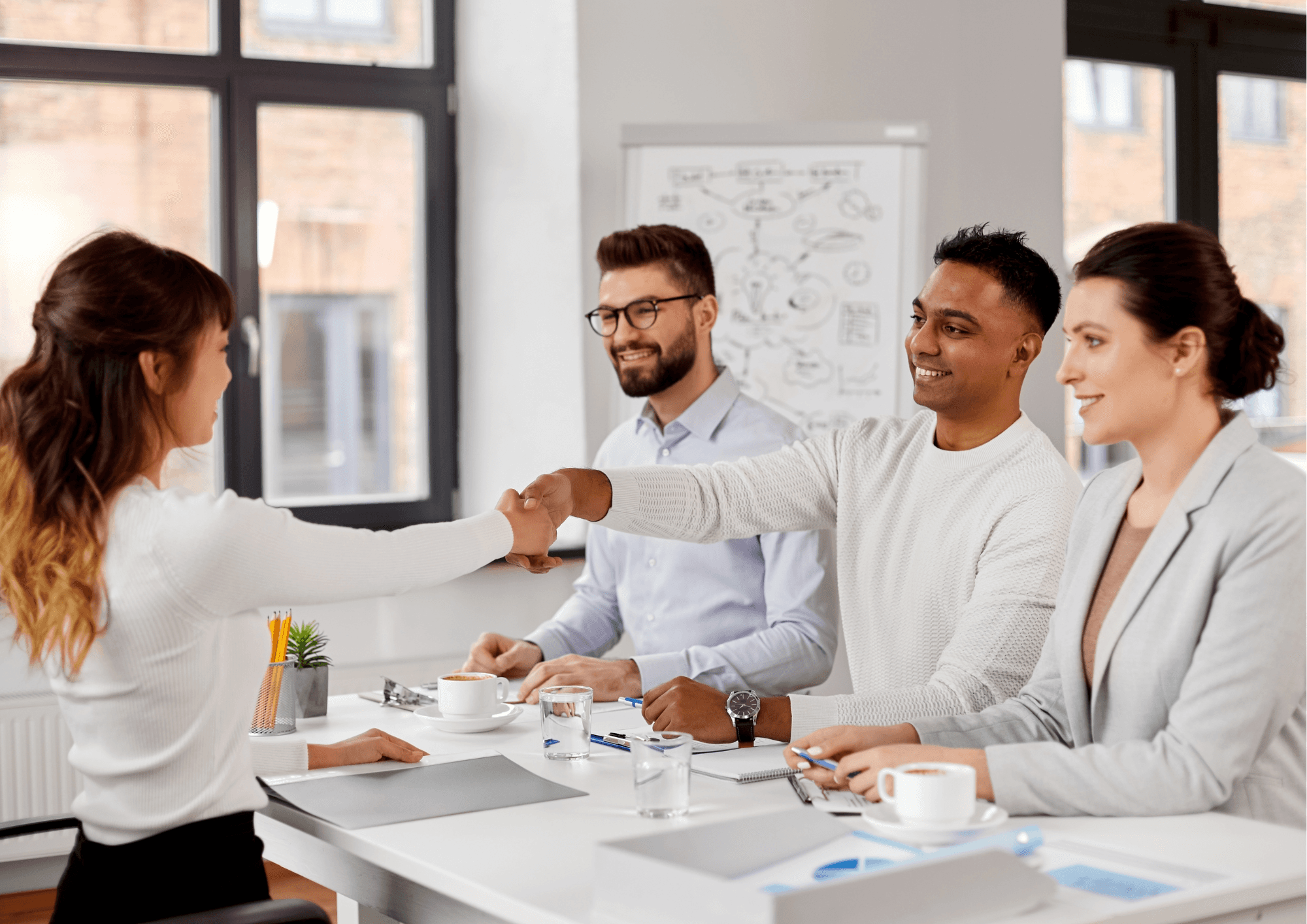 A professional interview setting with a candidate being welcomed by a diverse panel of interviewers in a modern office.