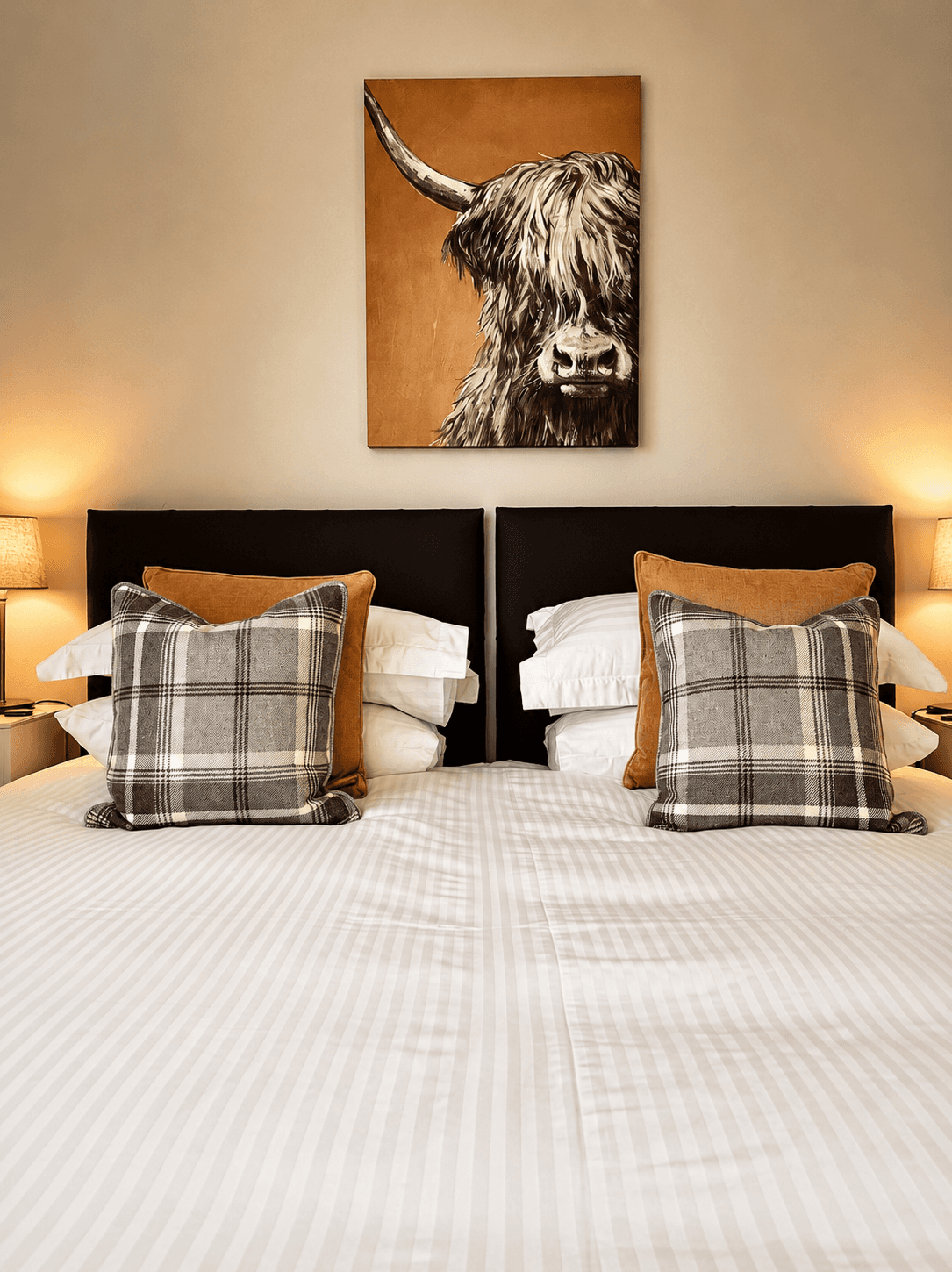 The Master Bedroom in Mar House complete with warm lighting, comfy bed and a painting of a scottish highland cow