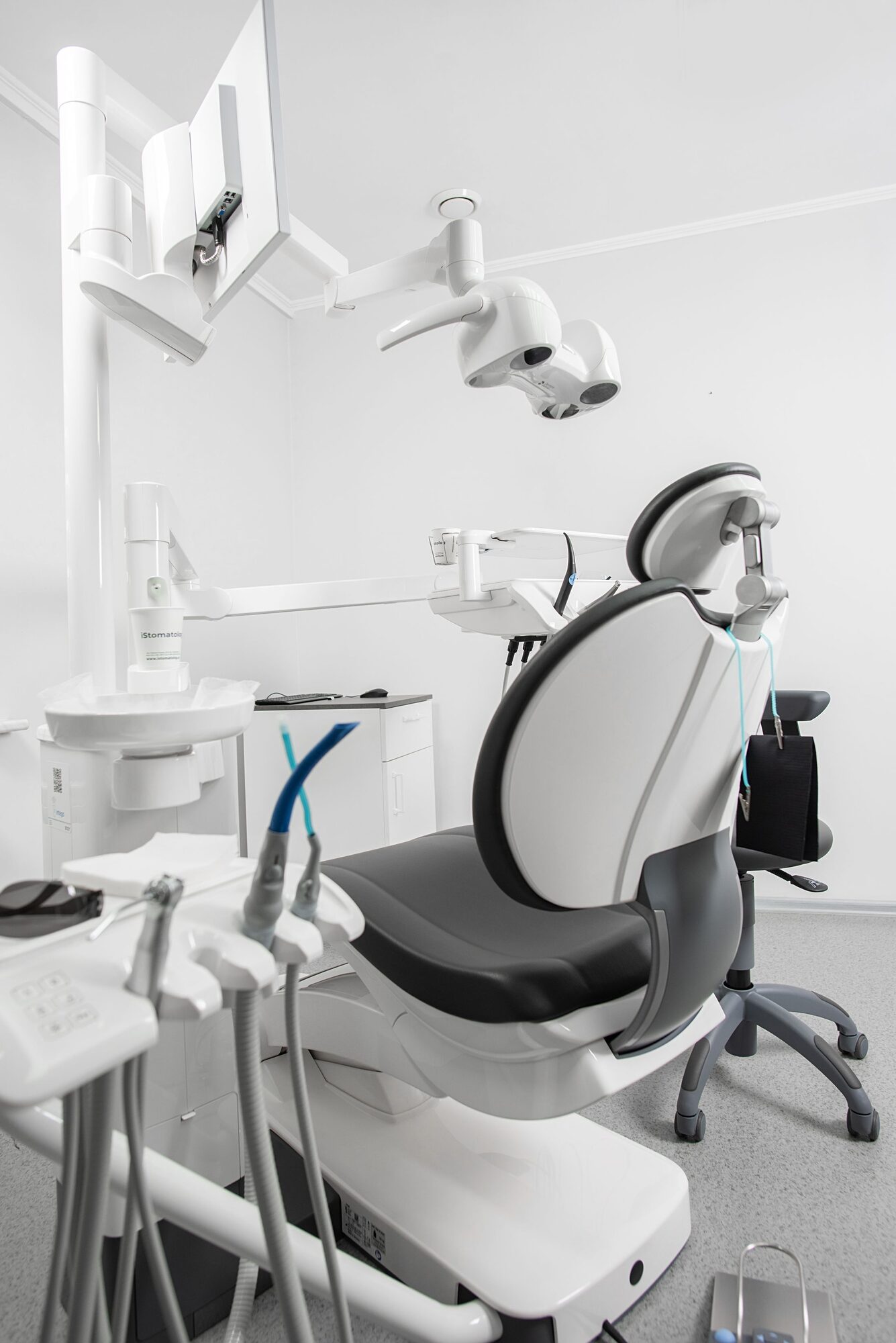A dental chair under a ceiling lamp in a calm treatment room