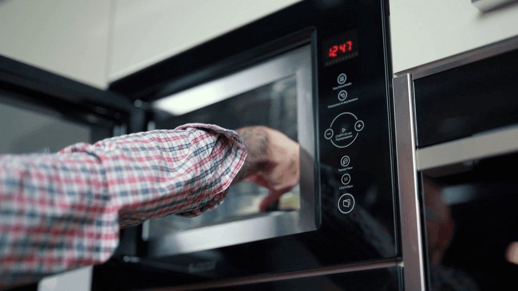 A man puts food in the microwave.
