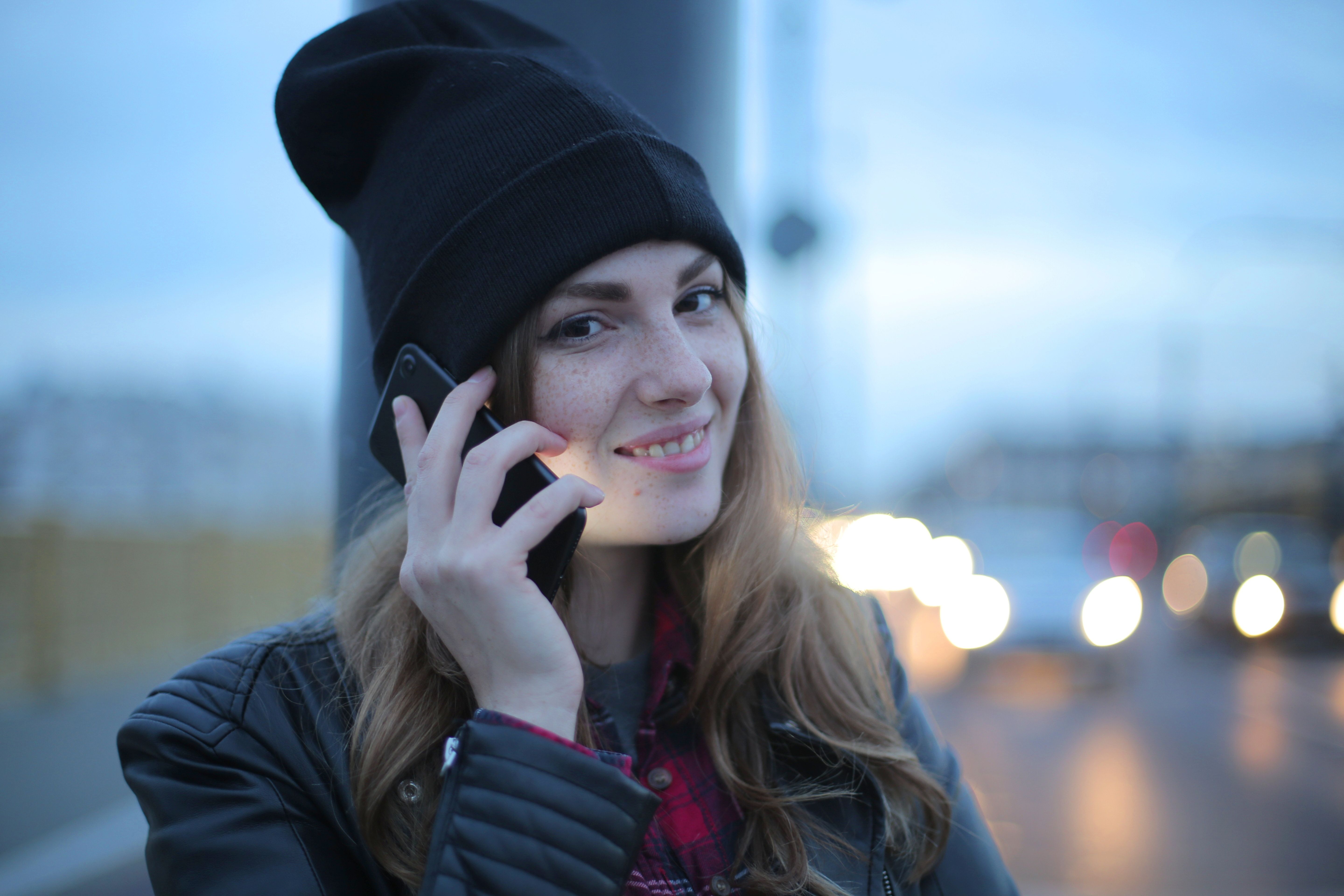 Femme souriante au téléphone en pleine rue le soir