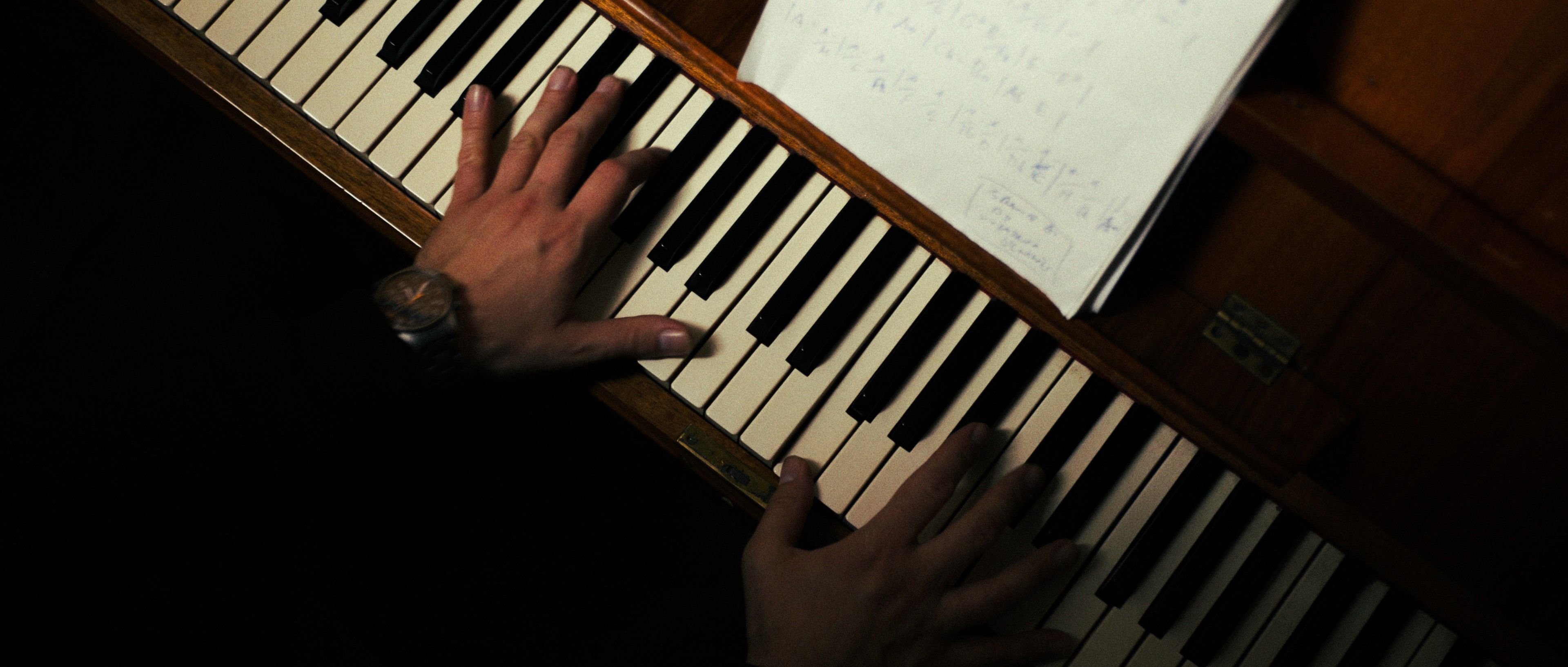 Close-up cinematic shot of musician's hands playing the piano, dramatic lighting.