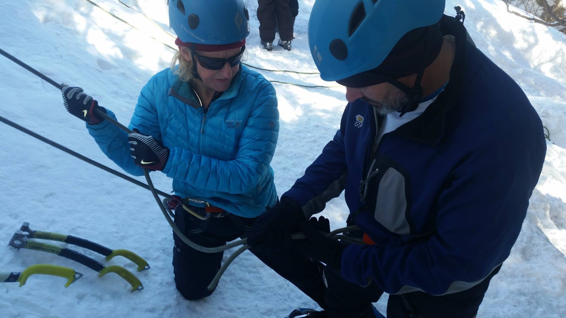 Ice climber ties into rope with tools stuck in ice