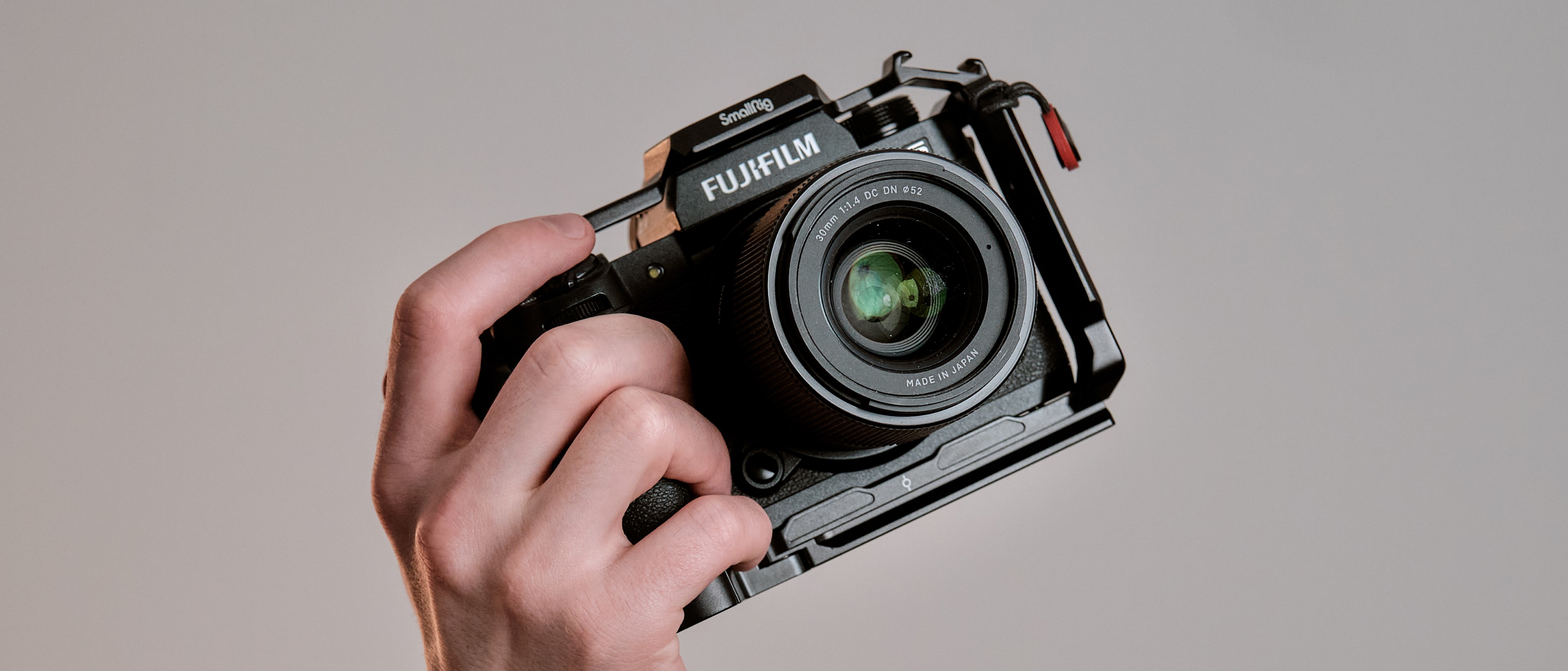 Fotografia przedstawiajaca dłoń trzymającą aparat fotograficzny marki FujiFilm 