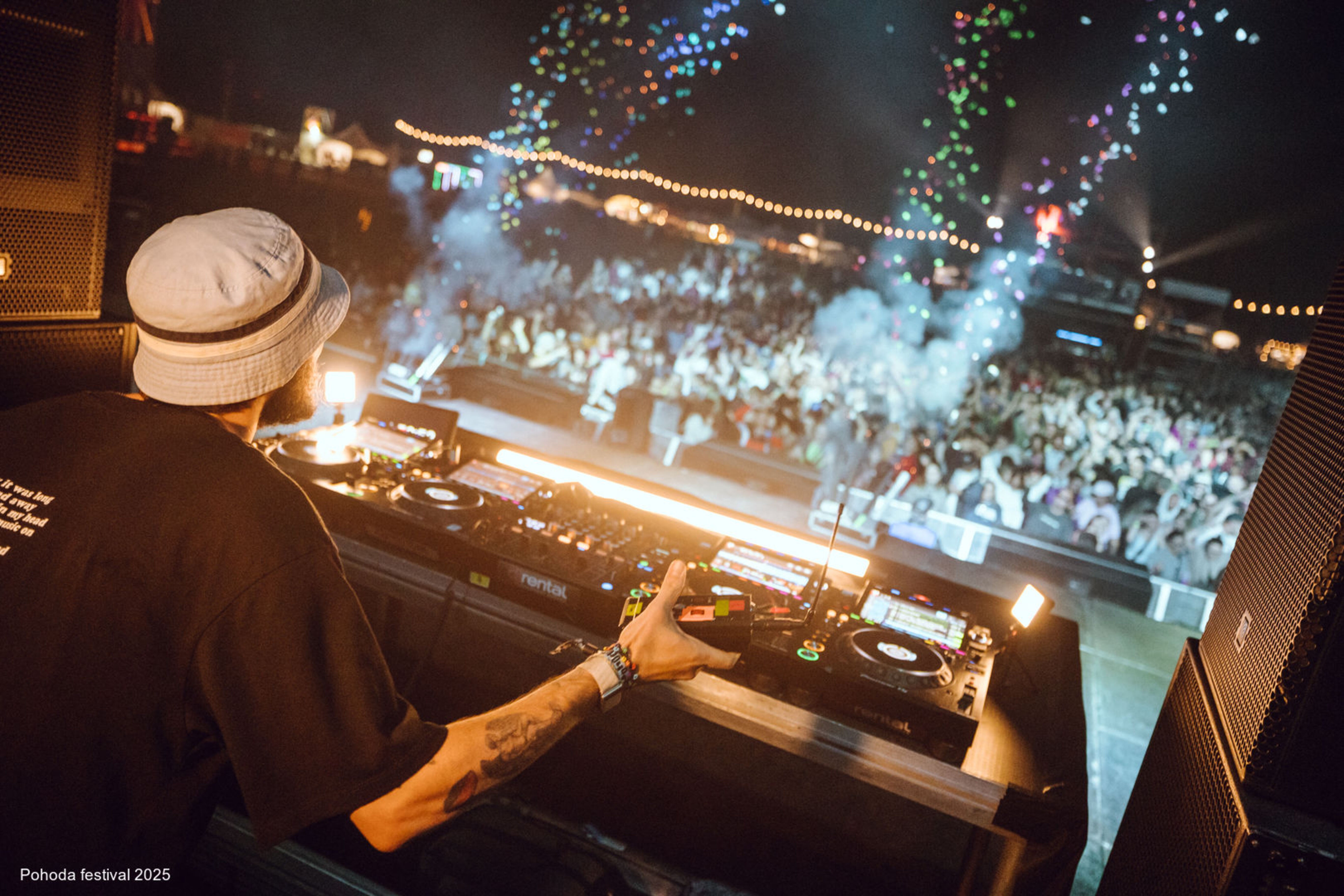 DJ performing on stage as festivalgoers dance beneath colorful lights at Pohoda Festival.