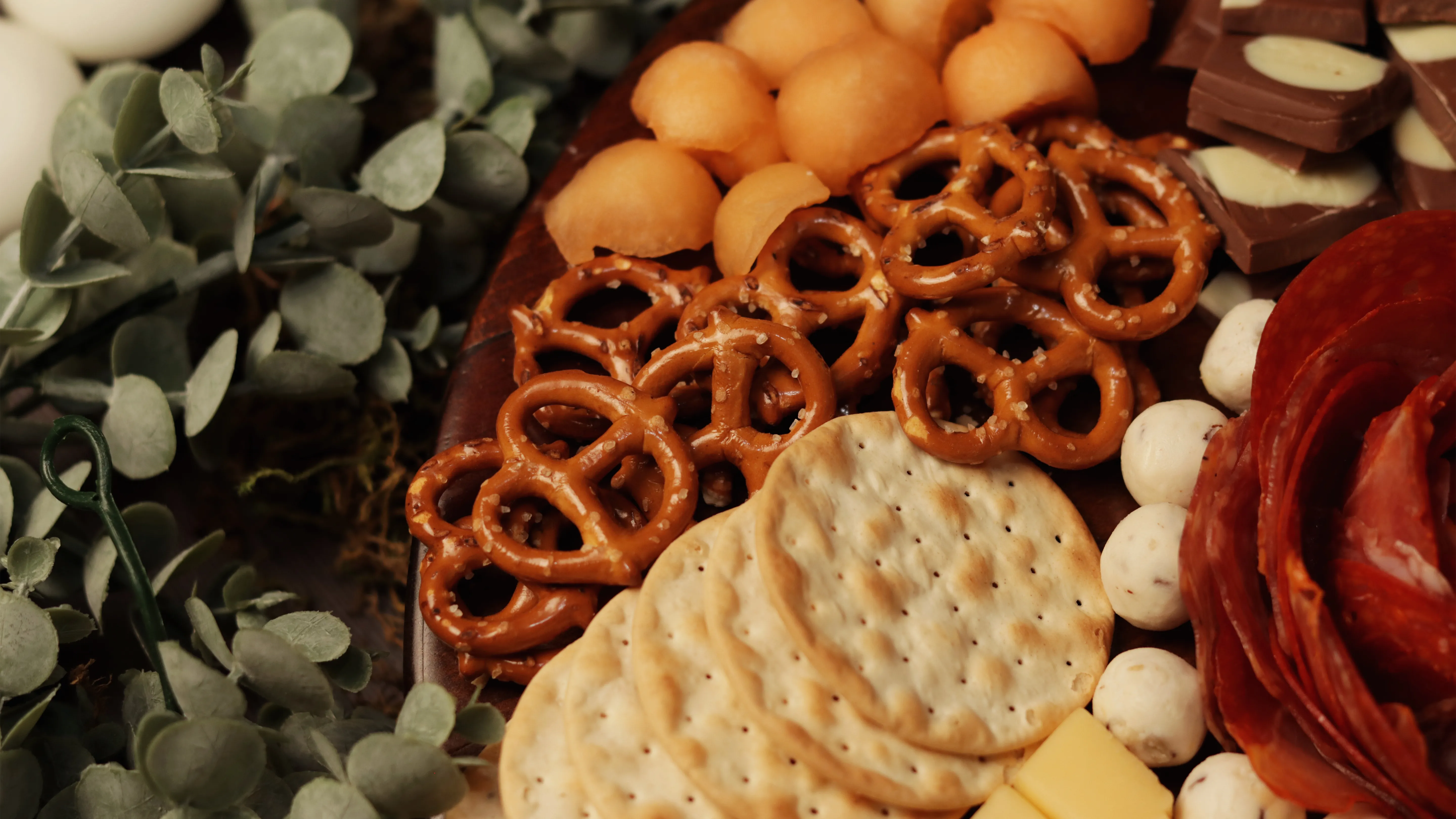 Detalle de pretzels, uvas y embutidos sobre tabla de madera