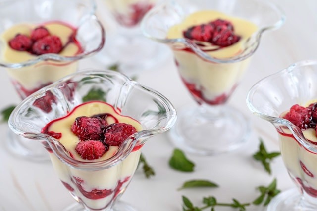 Small layered dessert dishes topped with raspberries