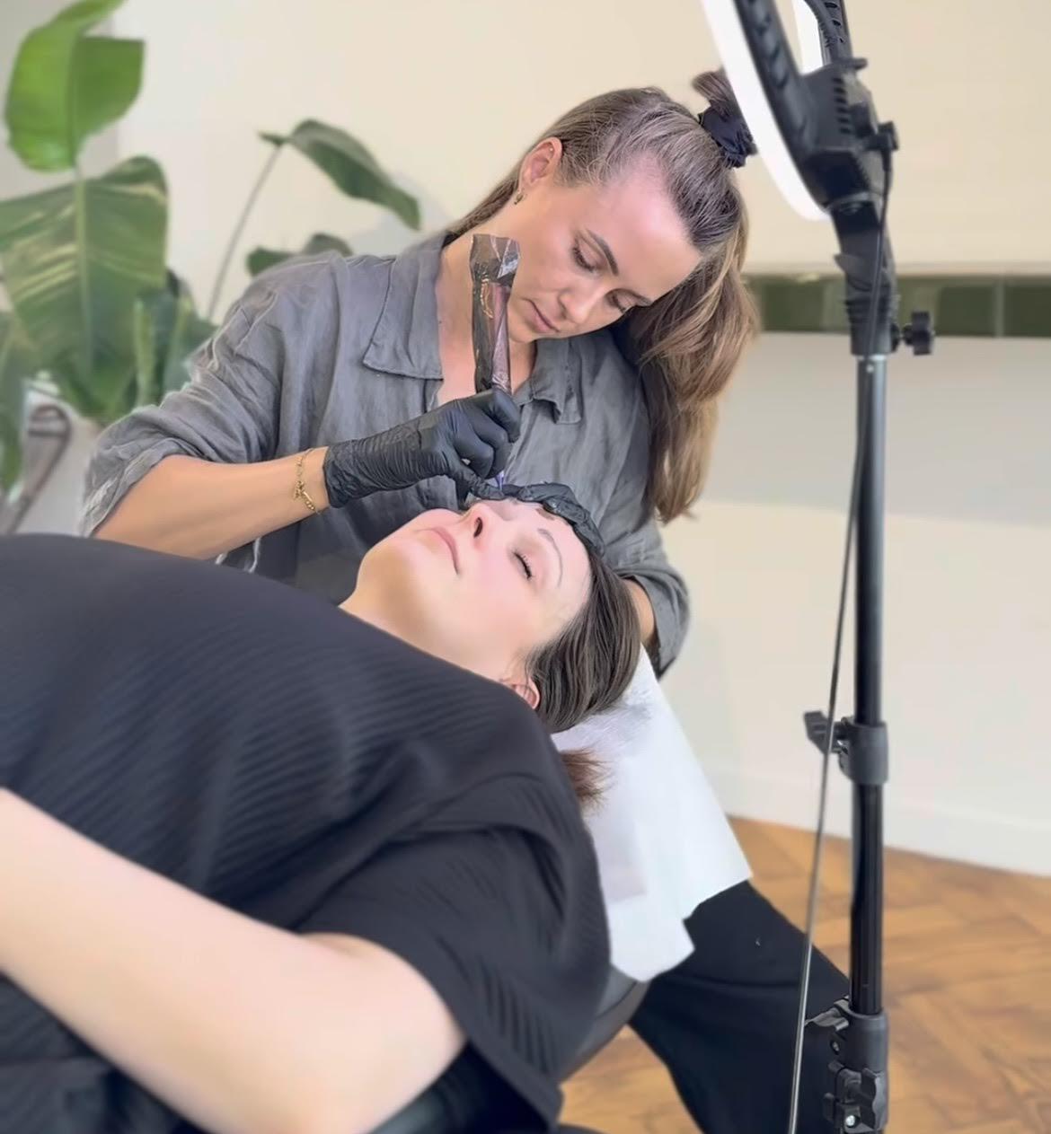 Vrouw die een cosmetische behandeling aan haar wenkbrauwen laat doen door een wenkbrauwspecialist.