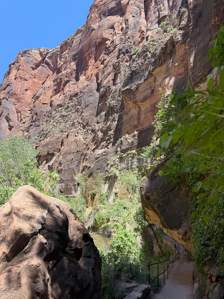Hiking trail passing underneath a massive rock formation inside the slot canyon.