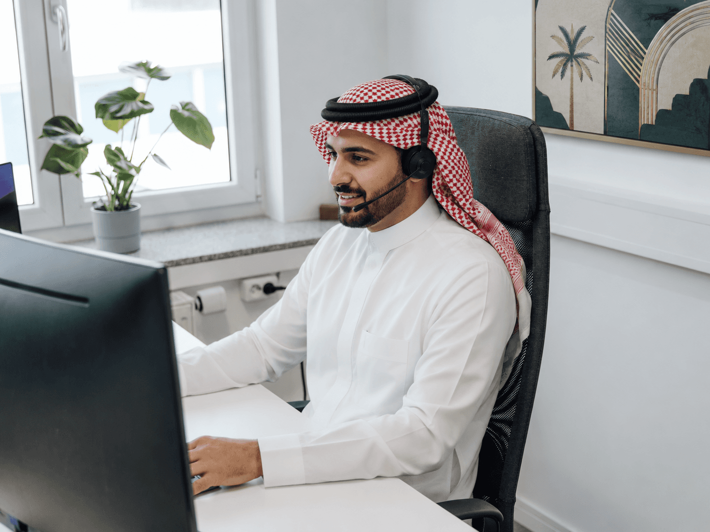 a man wearing a headset sitting in front of a computer