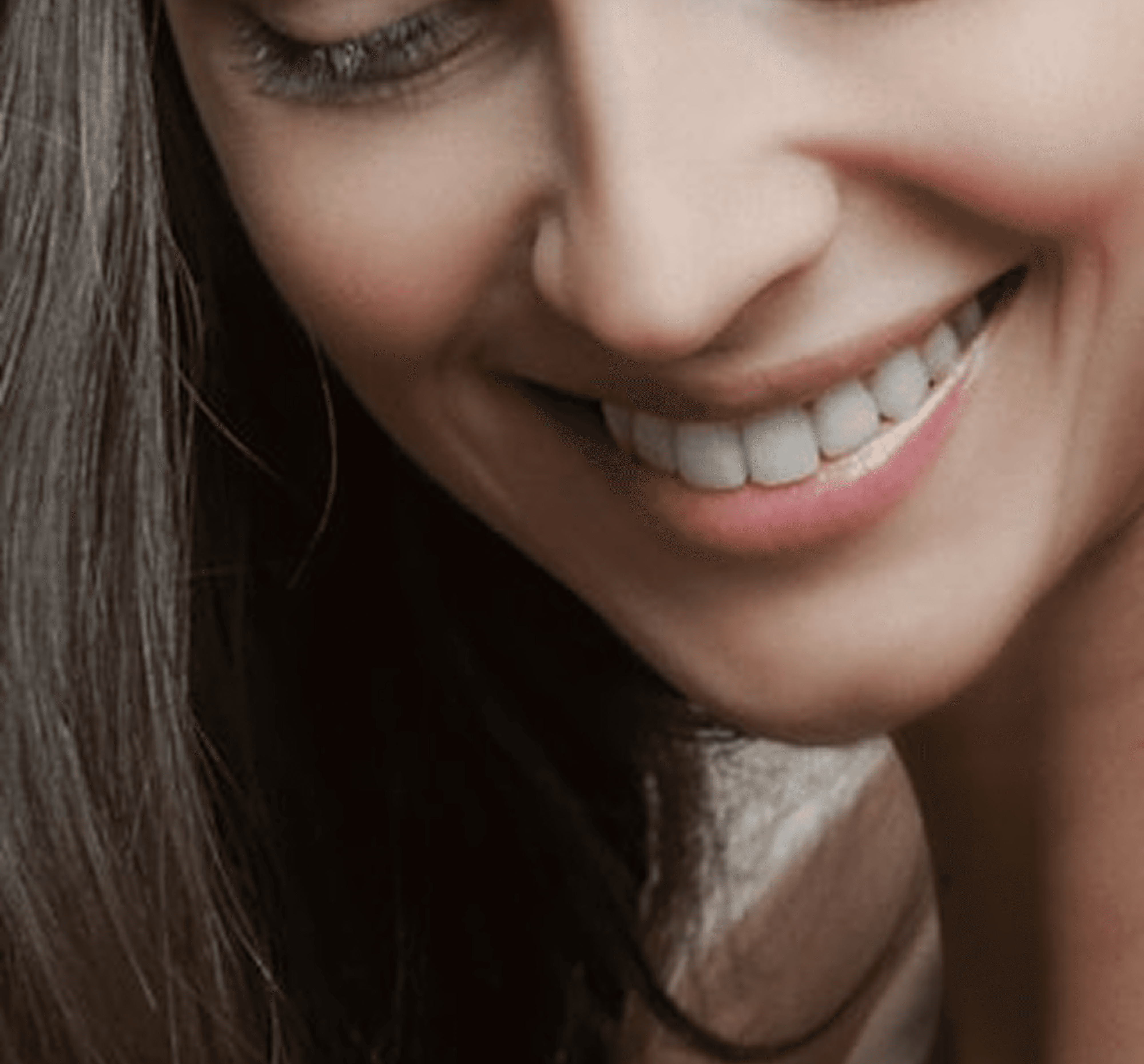 Smiling mouth with white teeth and dark hair.