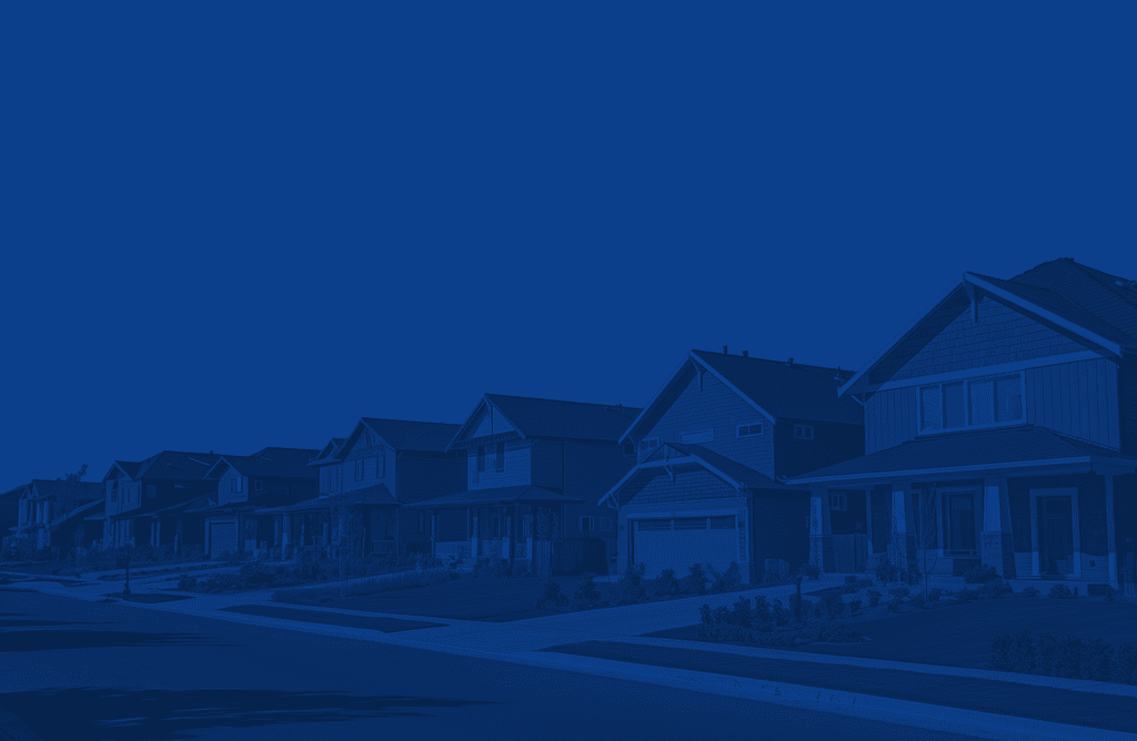 A row of residential houses silhouetted against a deep blue sky at dusk.