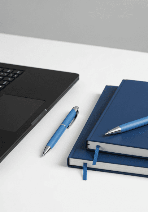 A smiling young man with crossed arms, wearing a plaid shirt and white t-shirt, poses against a dark background.