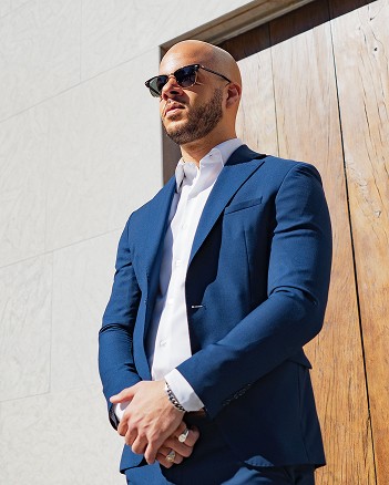 Alexander standing confidently in a blue suit