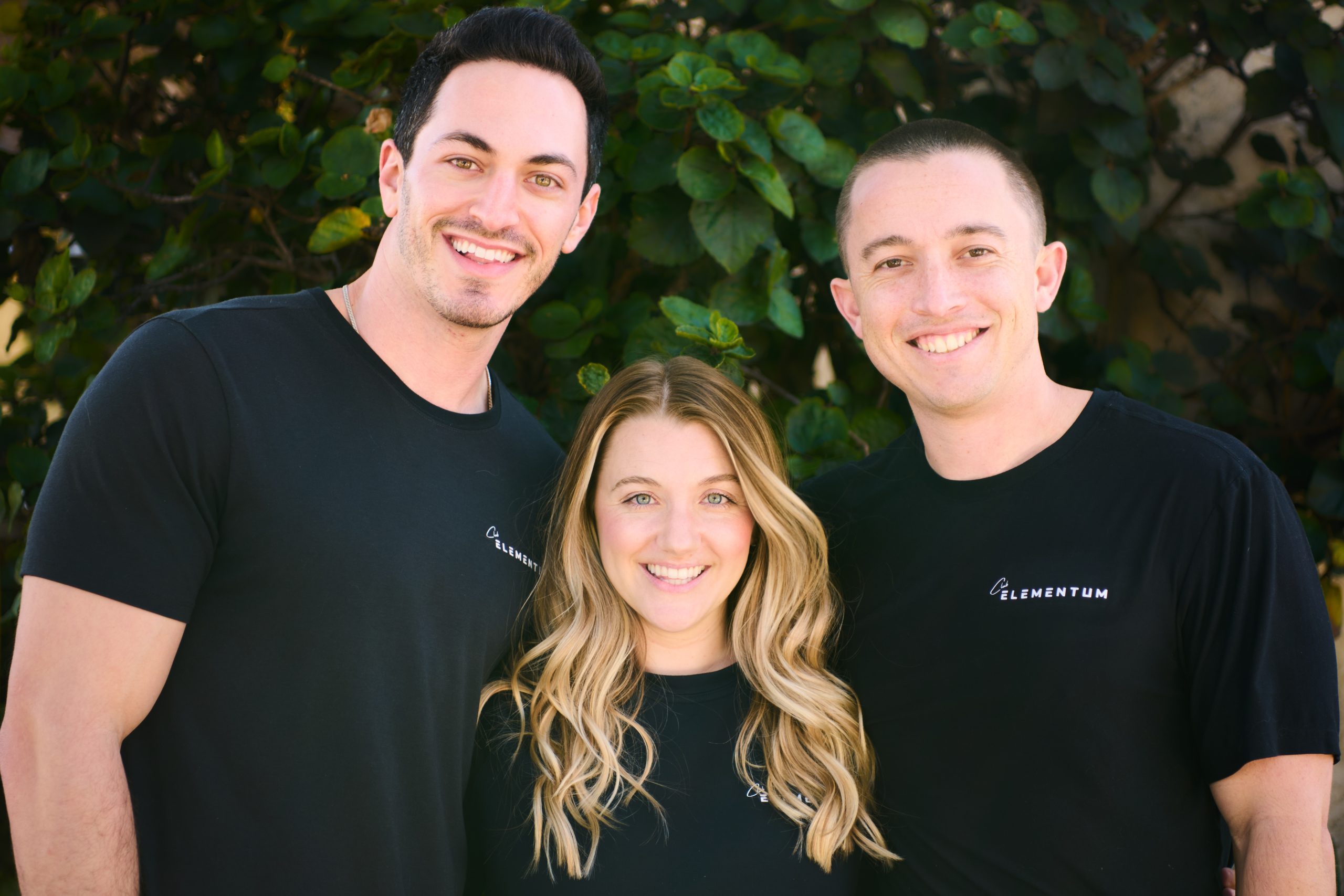 Three people sitting on a couch in a room looking at mobile devices